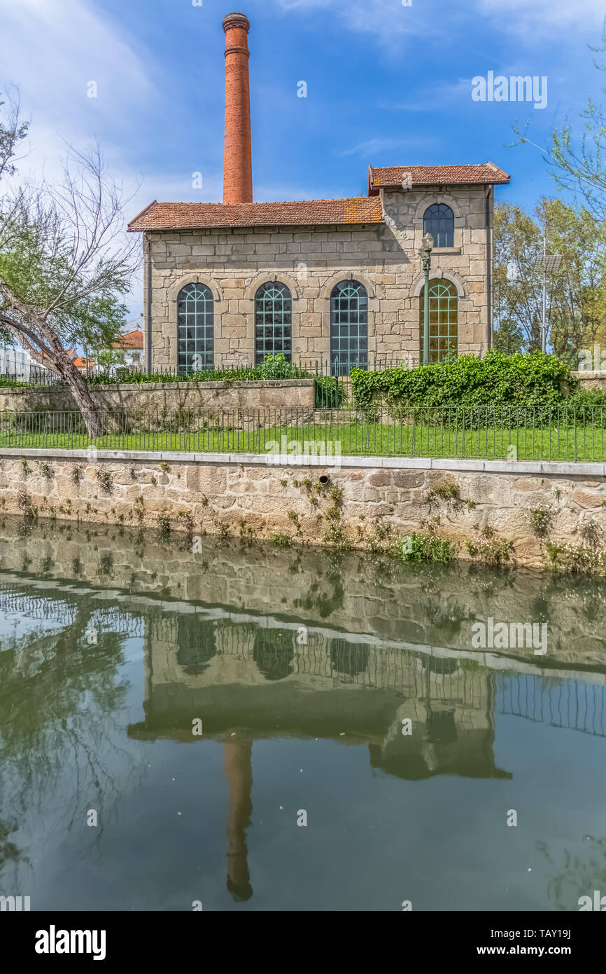Viseu / Portugal - 04 16 2019 : View of the Museum of electricity, building with chimney in industrial brick, mirrored on Paiva river, Portugal Stock Photo