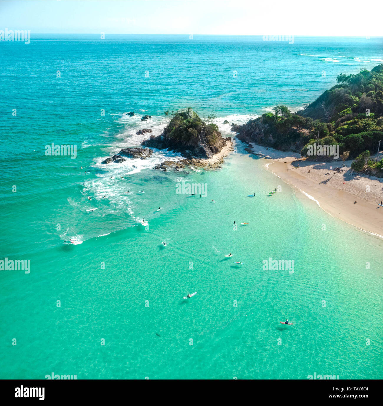 Aerial shot at sunrise over the ocean and white sand beach with swimmers and surfers enjoying summer Stock Photo