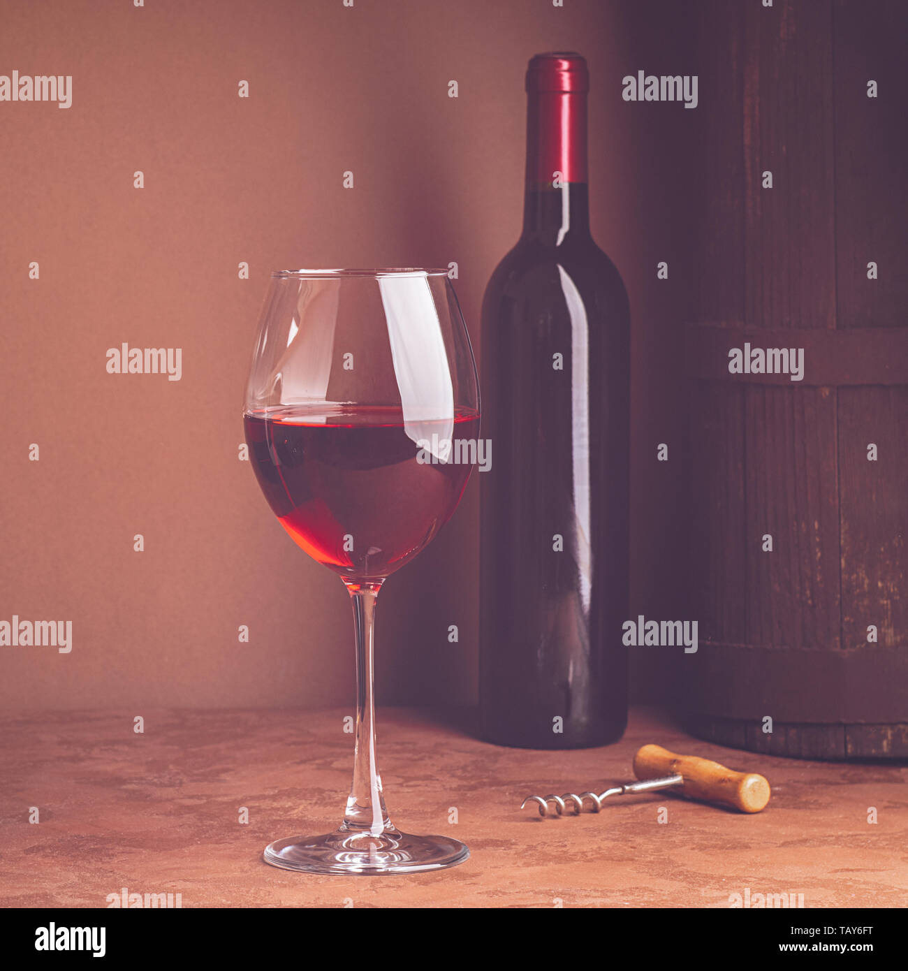A glass of red wine and a bottle on dark background. Copy space. Still life style dark. Selective focus. Stock Photo