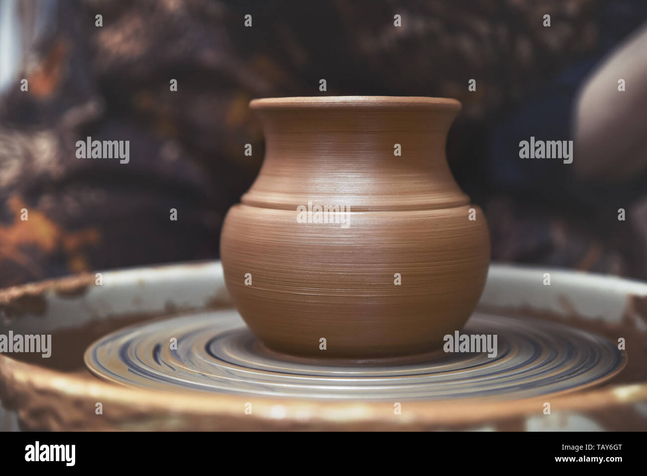 A new, rough, clay vessel on a potter's wheel. Pottery Stock Photo
