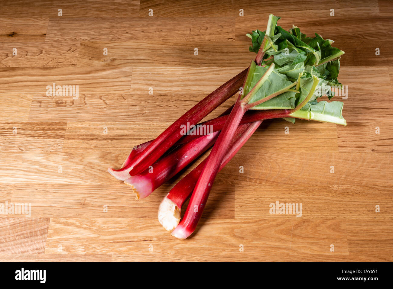Fresh red rhubarb stalks on a wooden table Stock Photo