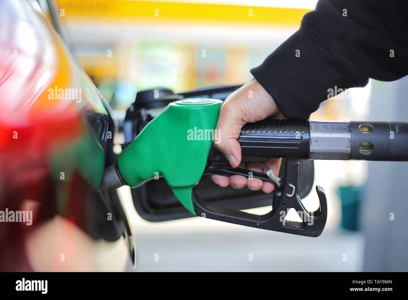 Close up hand holding green gasoline fuel nozzle and being fill gas