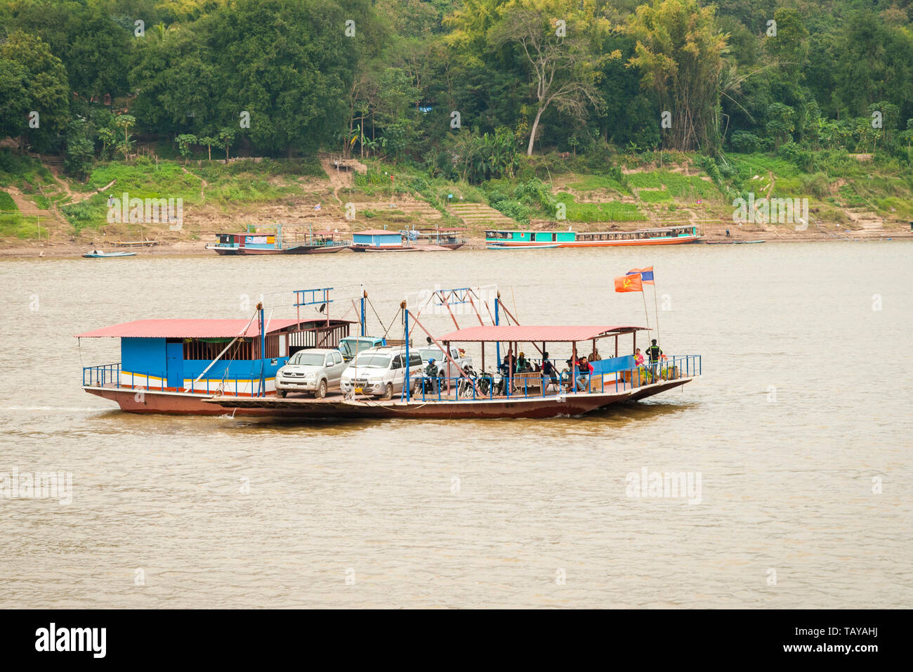 Luang Prabang, Laos - Feb 2016: Local ferry raft transporting cars, motorbikes and people over the Mekong River Stock Photo