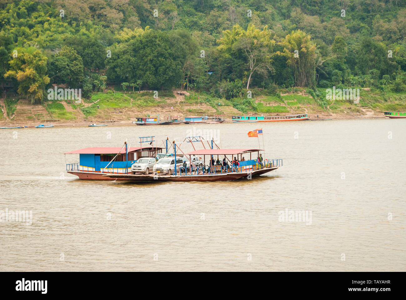 Luang Prabang, Laos - Feb 2016: Local ferry raft transporting cars, motorbikes and people over the Mekong River Stock Photo