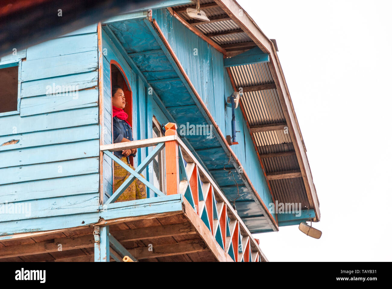 Nakaraj Nakhon, Laos - Feb 2016: Woman proudly standing and looking over the balcony from floating house on the ship on Mekong river Stock Photo