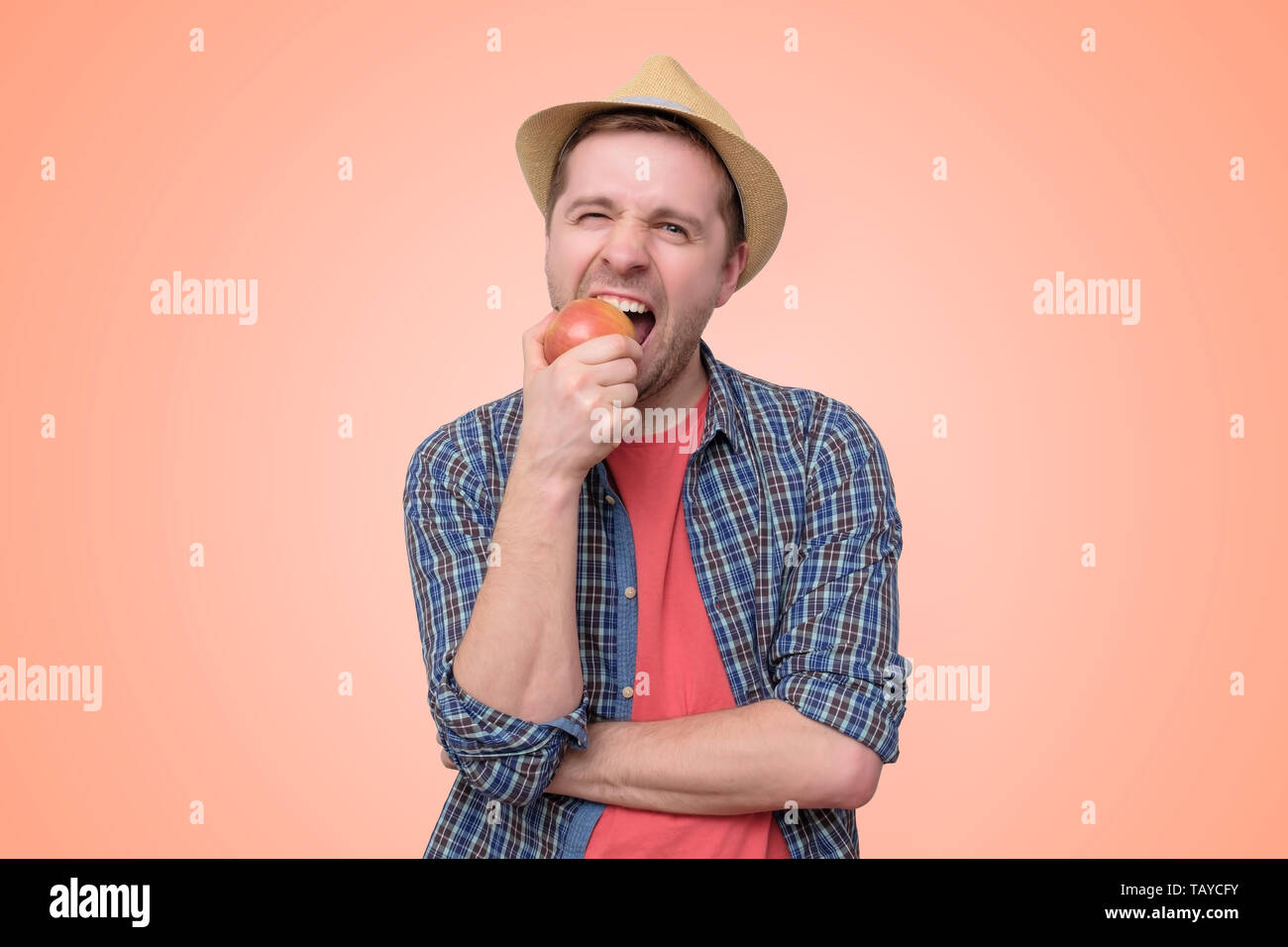 man in summer hat eatin gresh red apple. Stock Photo