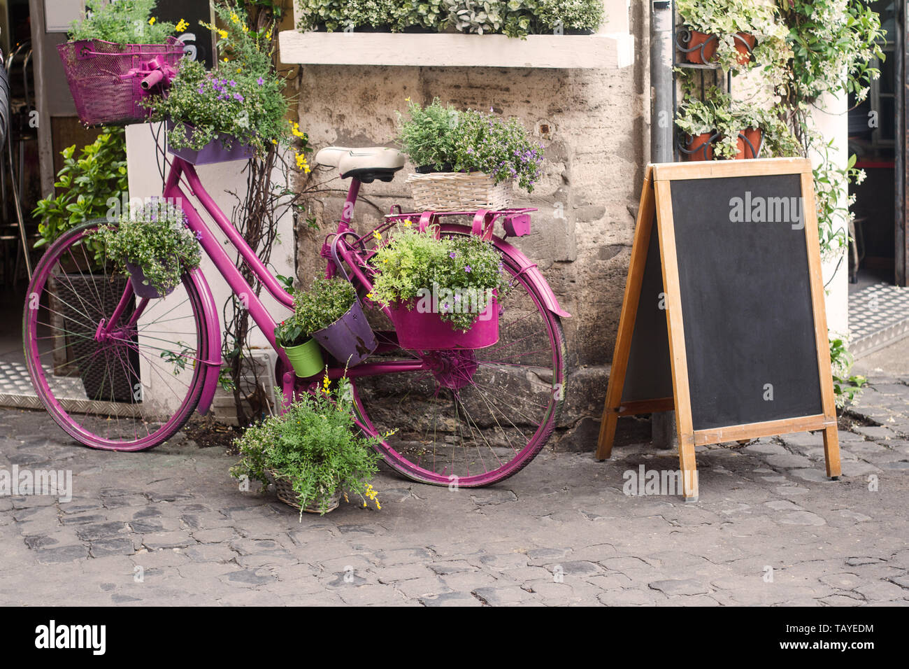 front view closeup of sidewalk retro street bistro store front with pink decorative bicycle and flowers next to empty menu chalk board Stock Photo