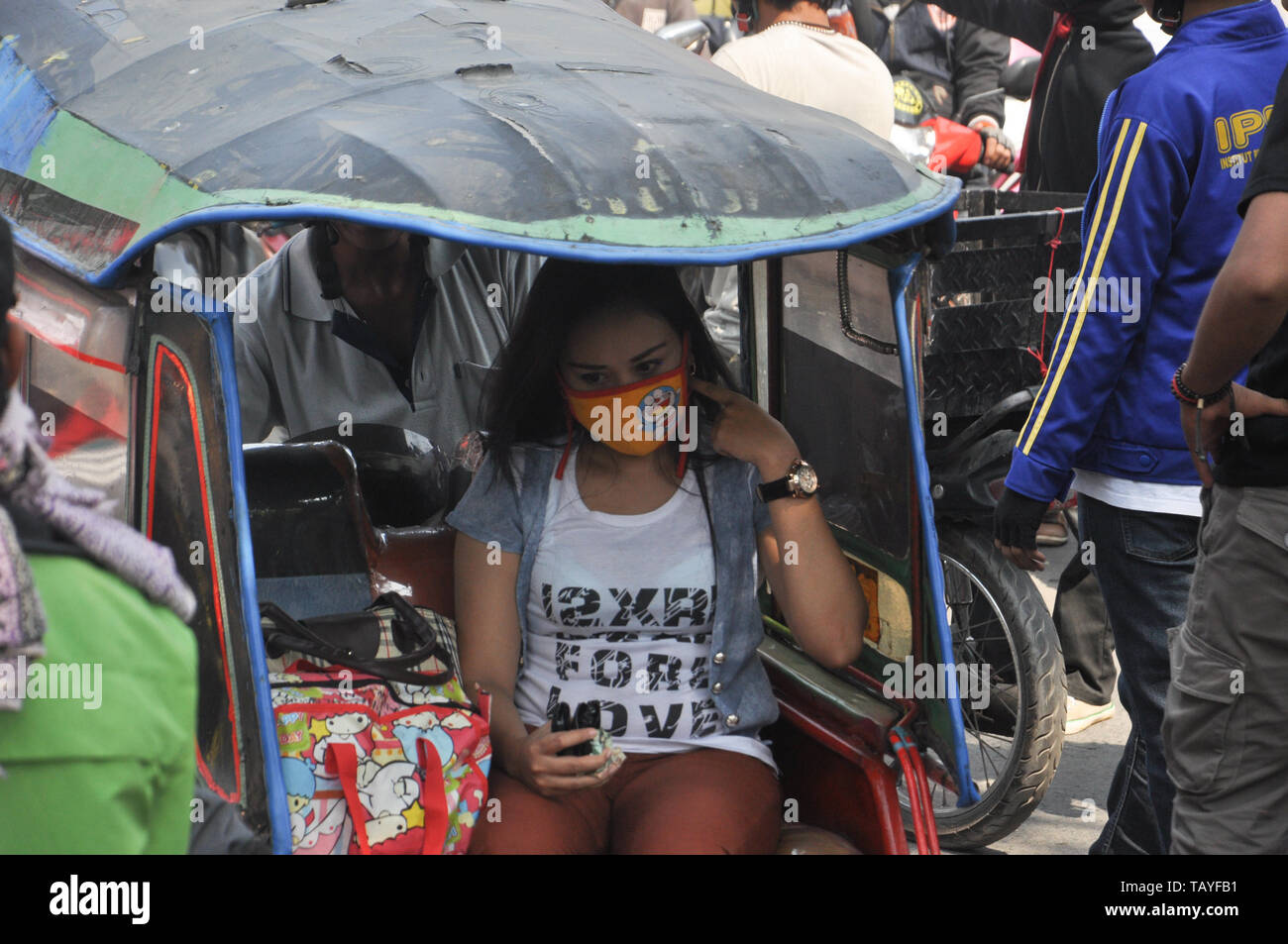 A woman sits in pedicab in the middle of sudents rally at Allaudin Street. University students all over Indonesia hold street rally to commemorate You Stock Photo
