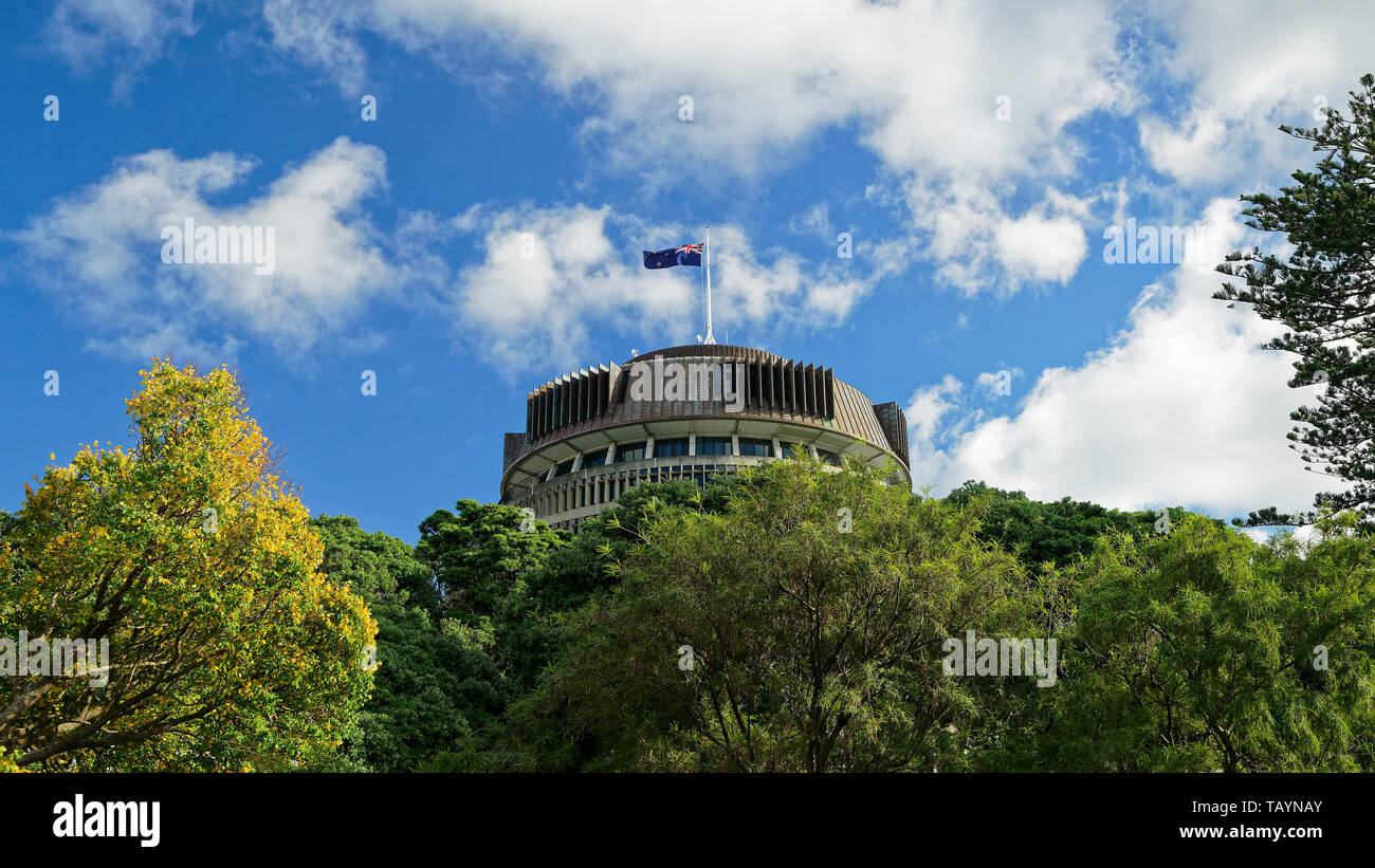 The Beehive above the treeline - New Zealand parliament building with flag flying on a sunny day Stock Photo