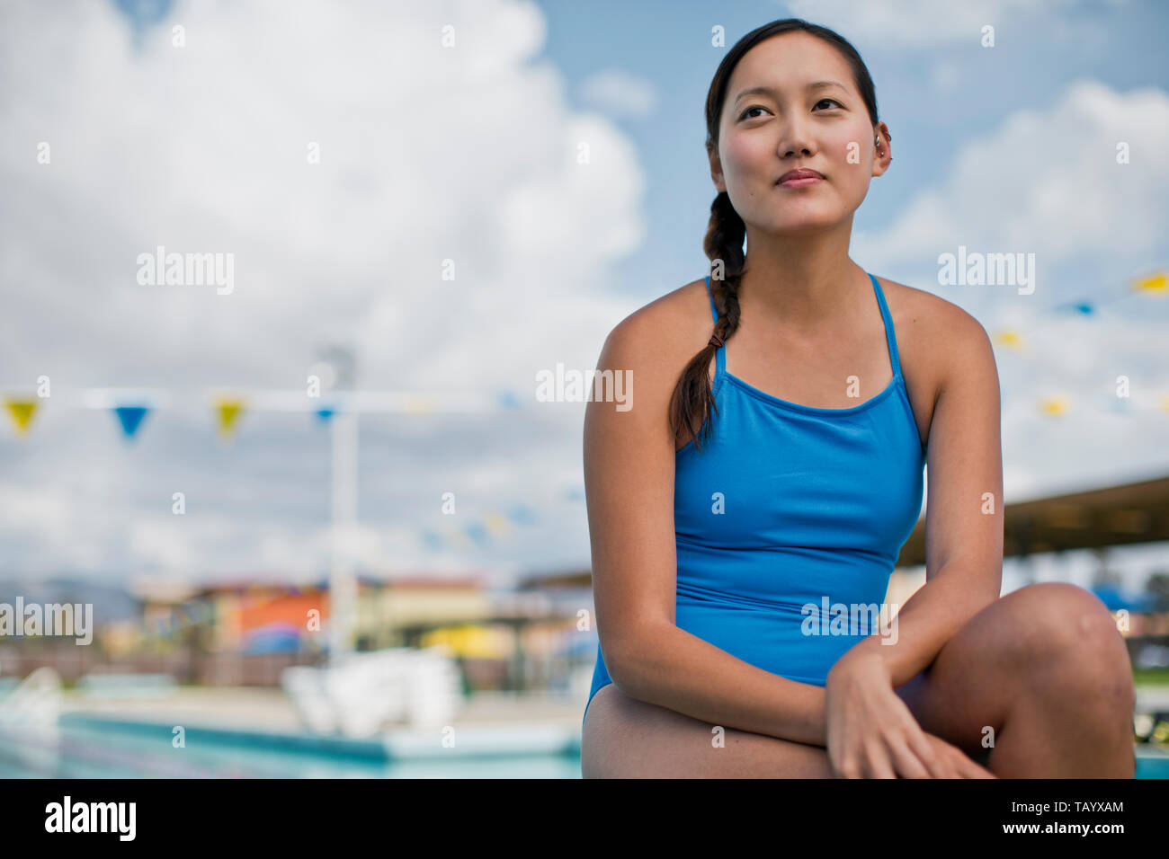 Young woman sitting poolside in her swimsuit. Stock Photo