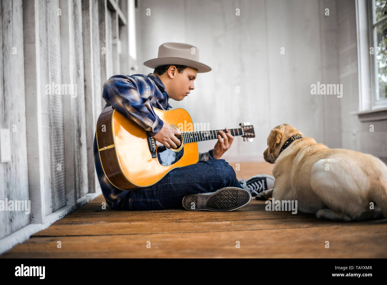 Teenage boy playing an acoustic guitar with his dog Stock Photo - Alamy