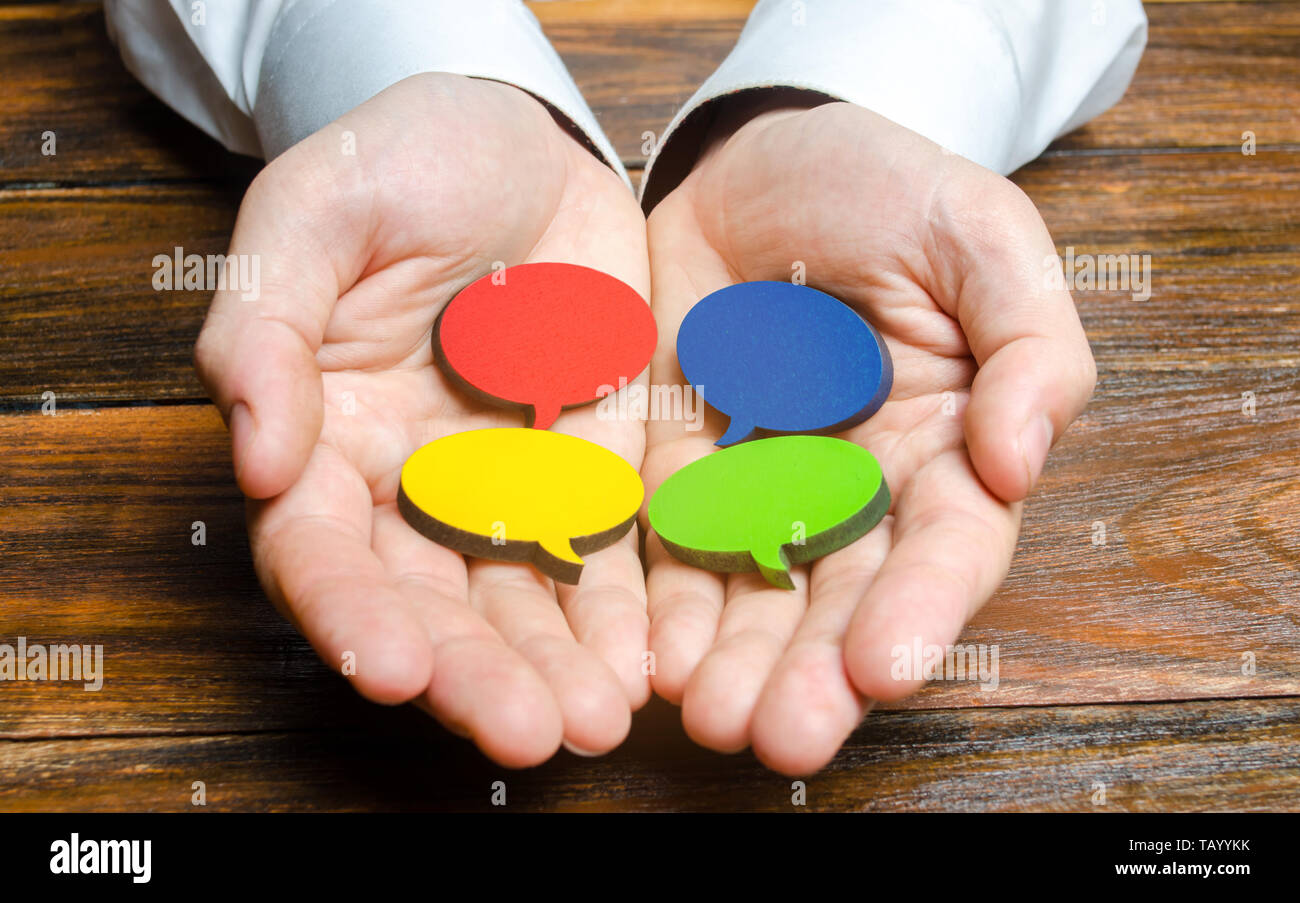 Man holds multicolored speech bubbles in his hands. Listen to other opinions and points of view, accepting criticism and comments. Reverse contact wit Stock Photo