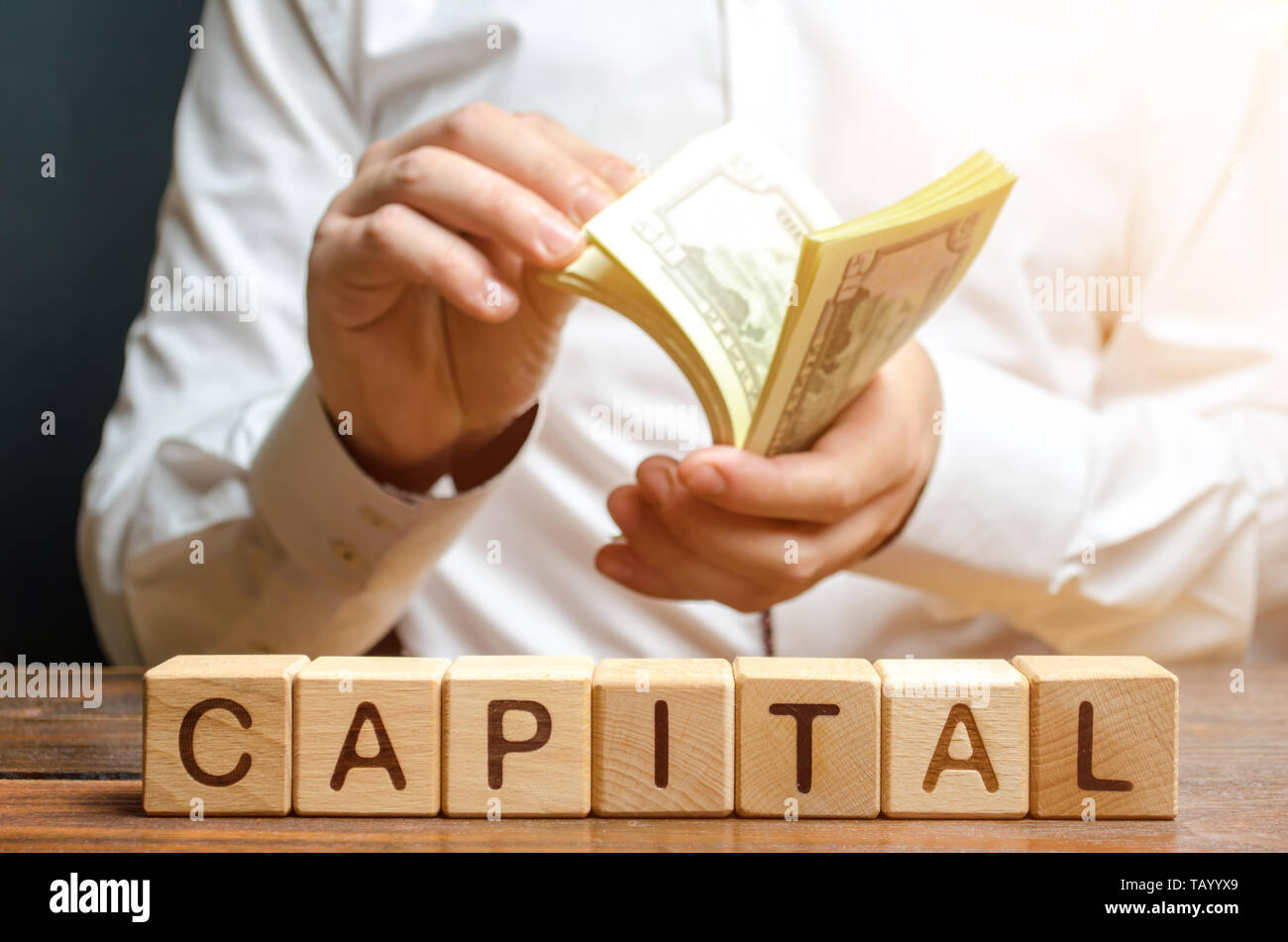 Businessman counts money on the background of the caption Capital. Capitalism, capital increase and influence. Financial liberalization of developing  Stock Photo