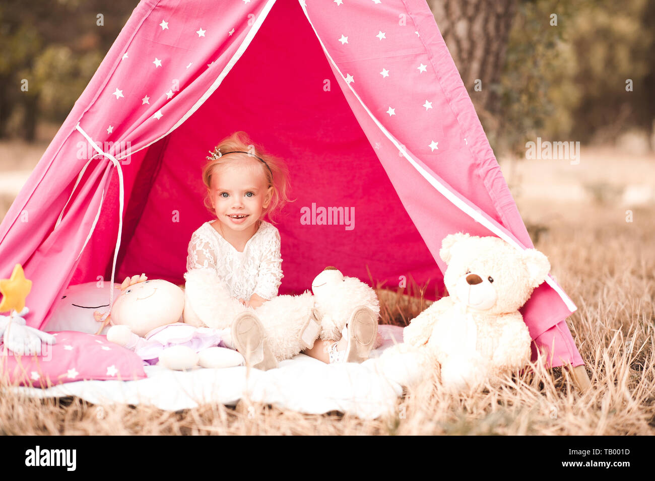 Cute baby girl 2-3 year old sitting playing with toys at back yard outdoors Stock Photo