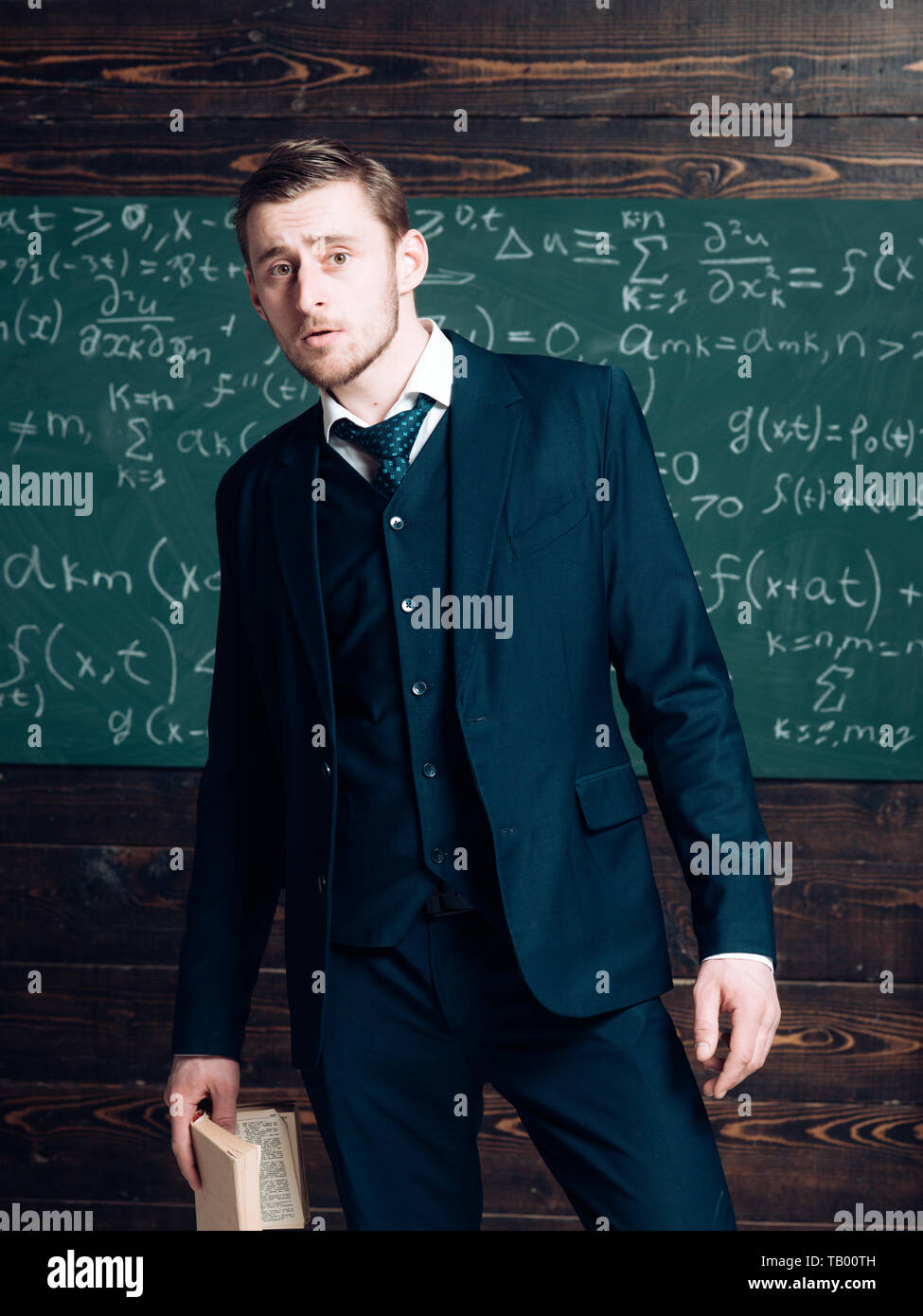 Caught on cheating. Man formal wear classic suit looks smart, chalkboard background. Man noticed cheating during exam test lesson. Teacher wondered of Stock Photo