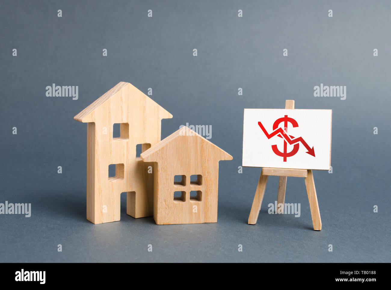 Two wooden houses and a poster with a symbol of falling value. concept