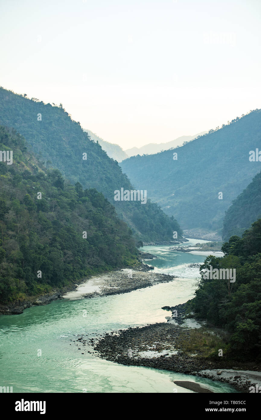 Stunning view of some green mountain peaks with the Sacred Ganges River flowing between them in Rishikesh, India. Stock Photo