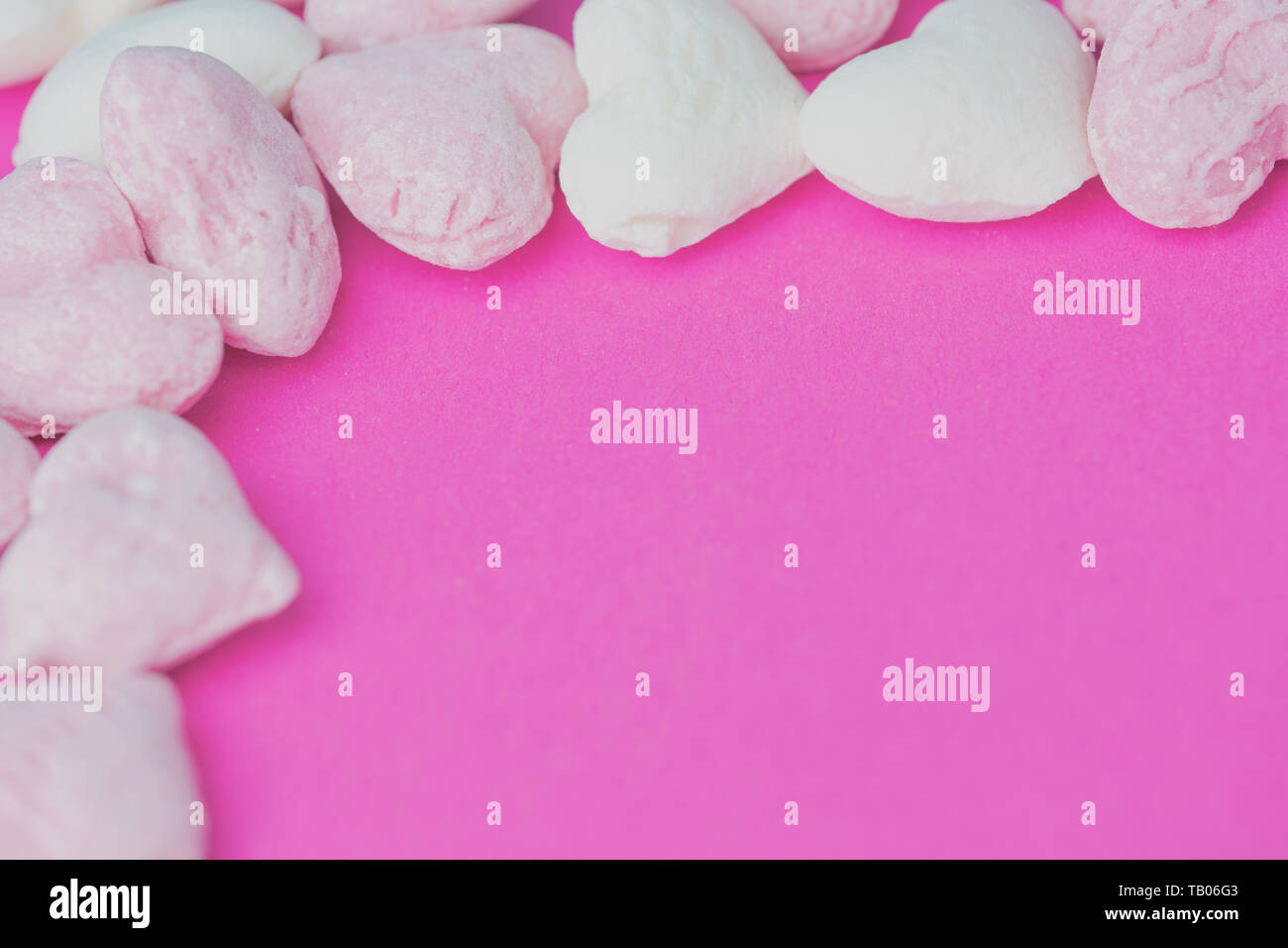 heartshaped pink and white hard candies on a pink background with copy