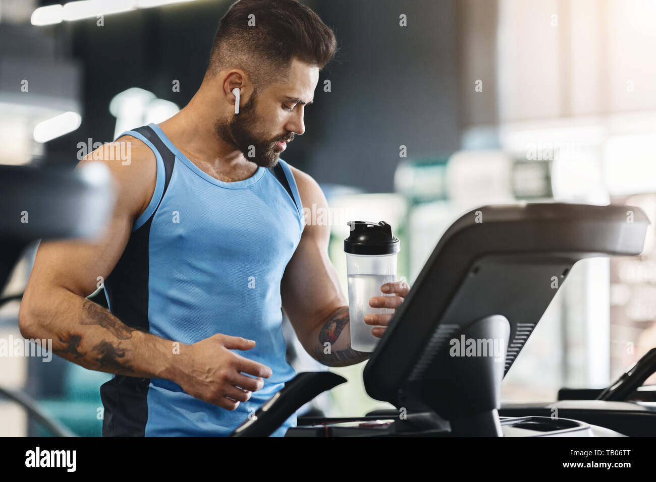 Sportsman holding bottle of water on treadmill at gym Stock Photo - Alamy