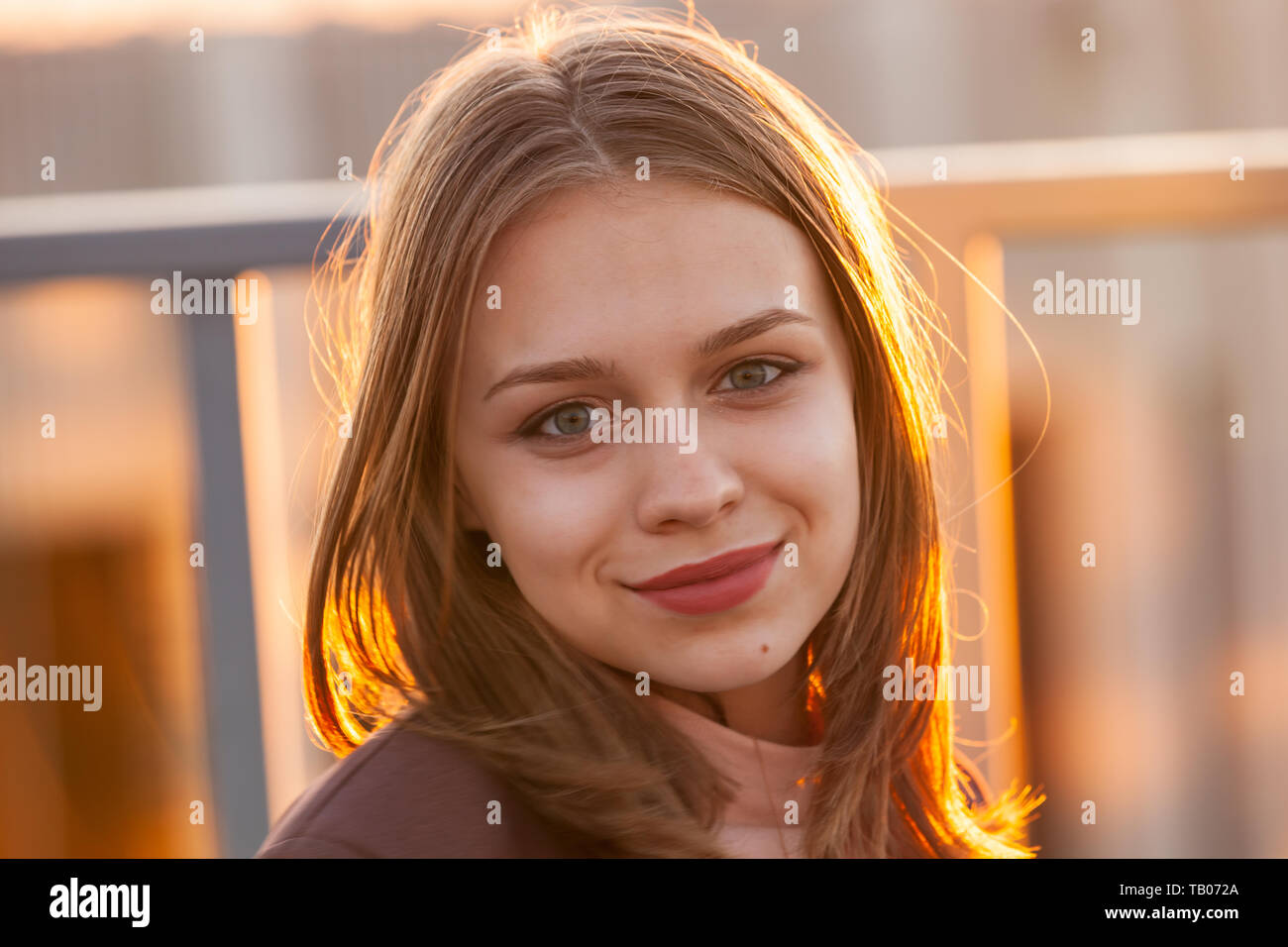 Beautiful smiling teenage girl, close up outdoor portrait with back-lit sunlight Stock Photo