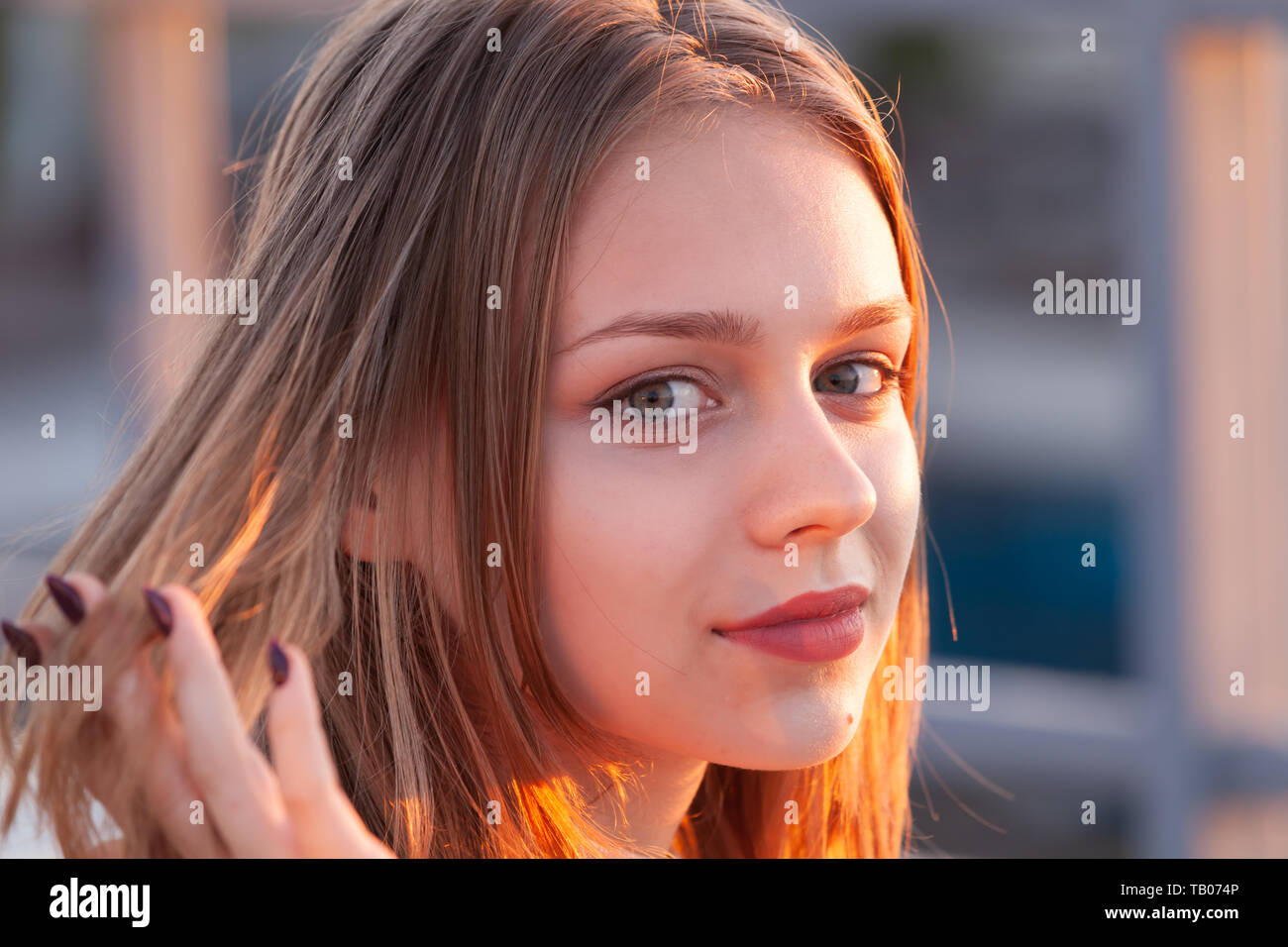 Beautiful blond European teenage girl, close up outdoor portrait with back-lit sunlight Stock Photo