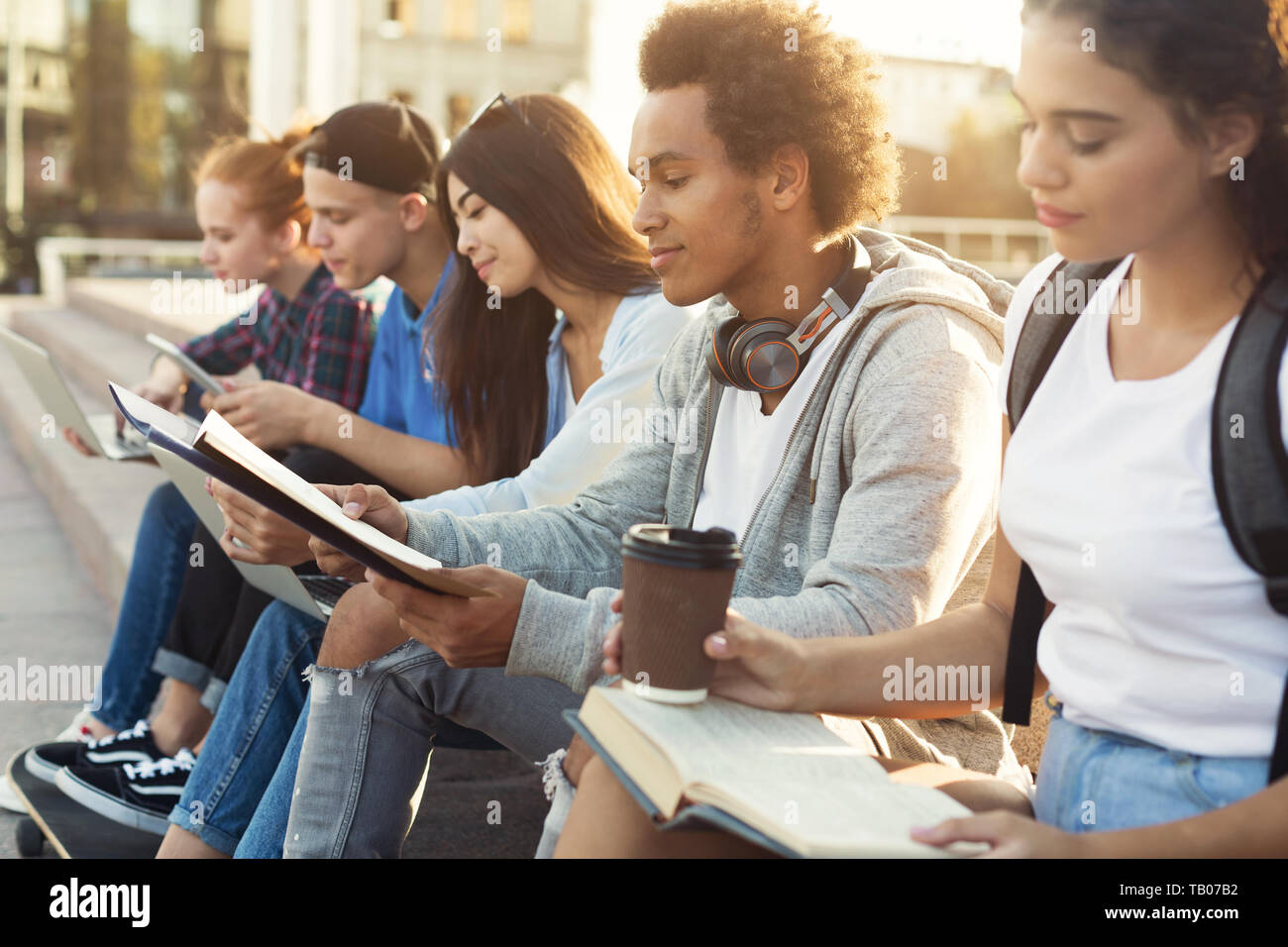 Teenage Diverse Students Studying Outdoors in Evening Stock Photo