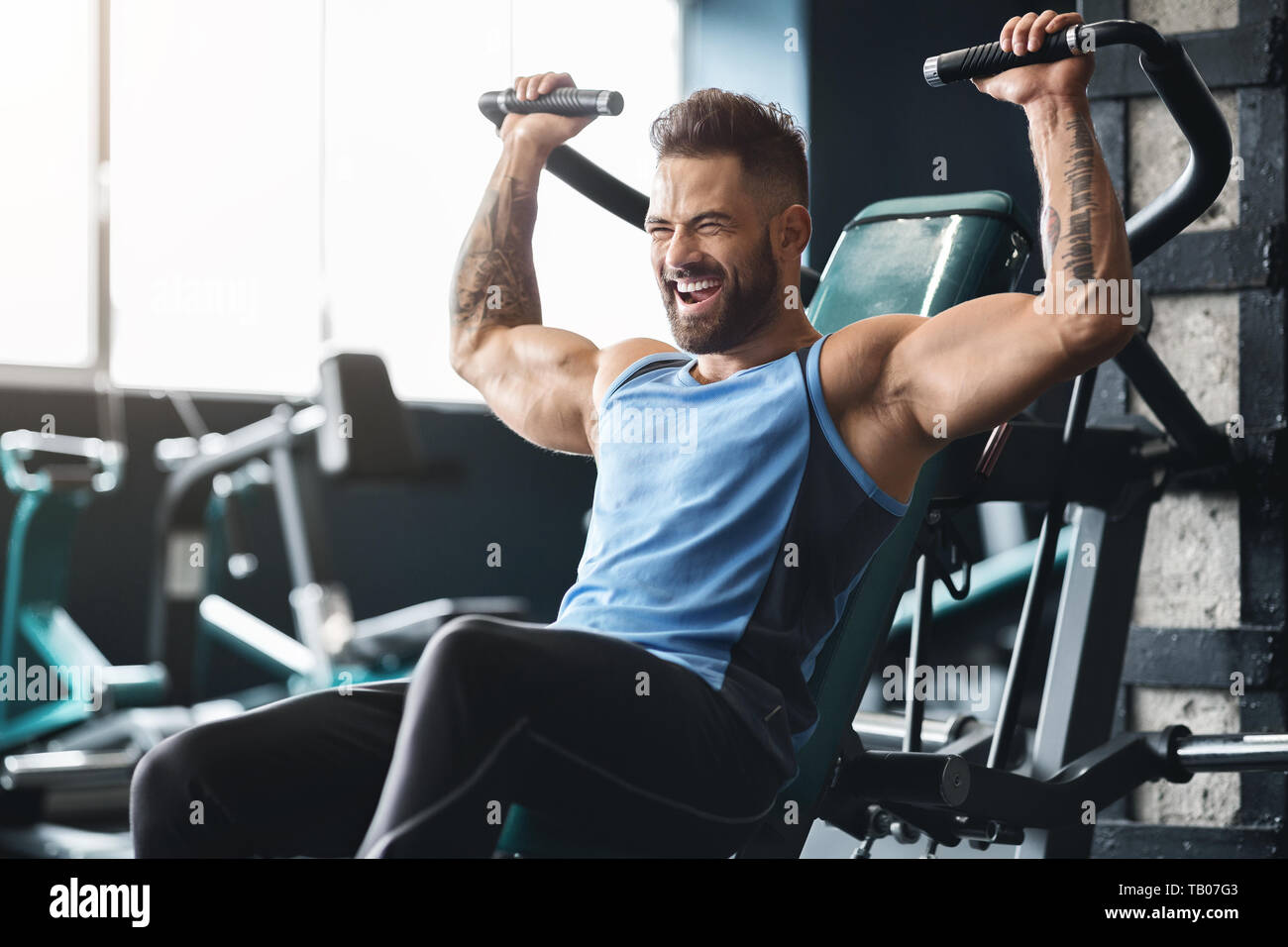 Handsome muscular man working out hard at gym Stock Photo