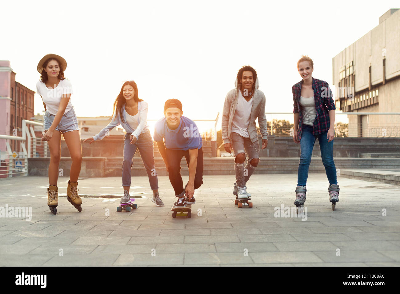Group of smiling teenagers with roller skates and skateboard Stock Photo
