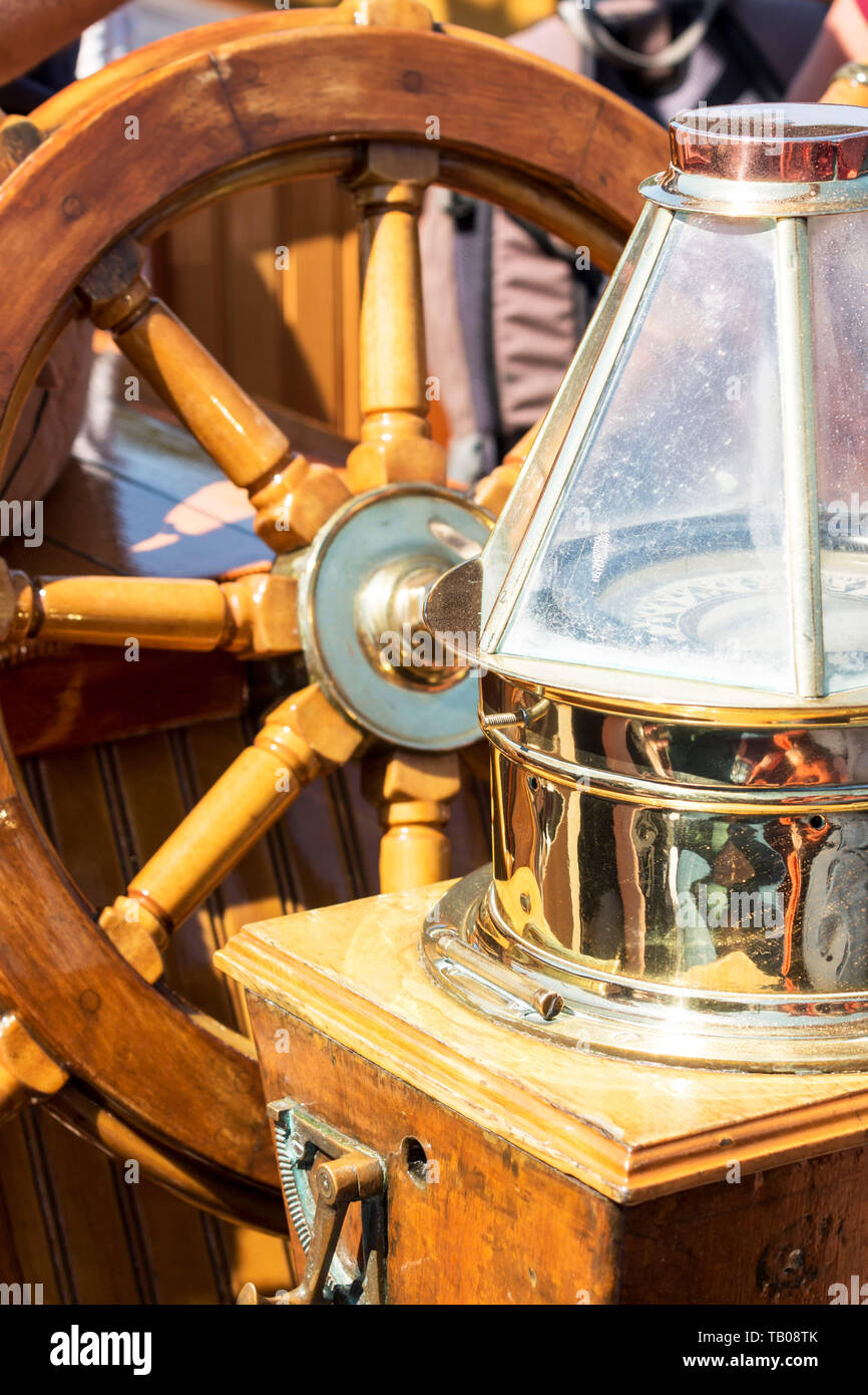 A wooden steering wheel ann vintage compass shine in the sunlight on a ...