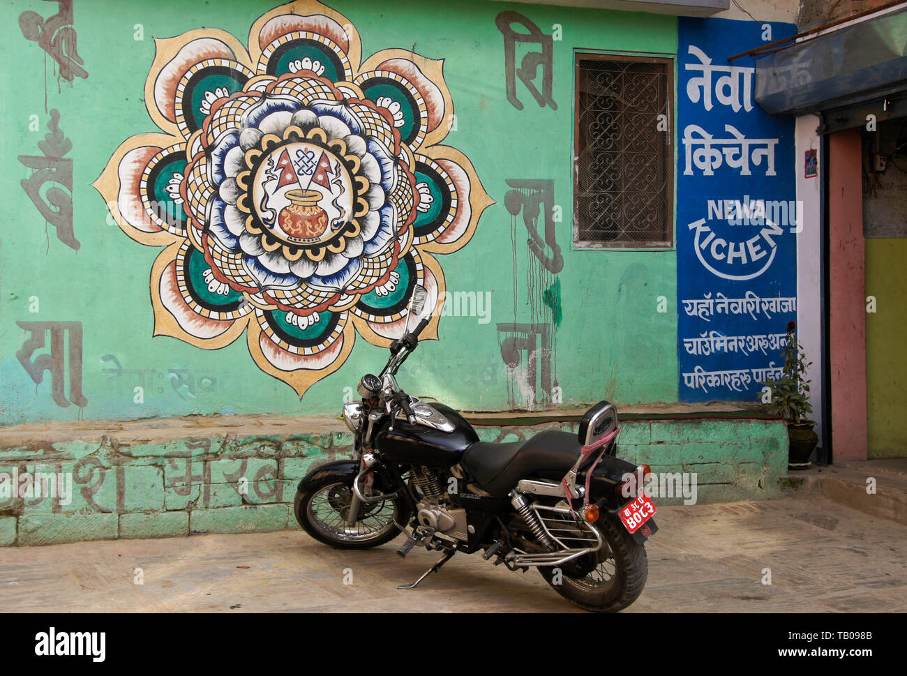 Motorcycle parked outside a Newari restaurant with a beautiful design on its exterior wall, Dhulikhel, Nepal Stock Photo