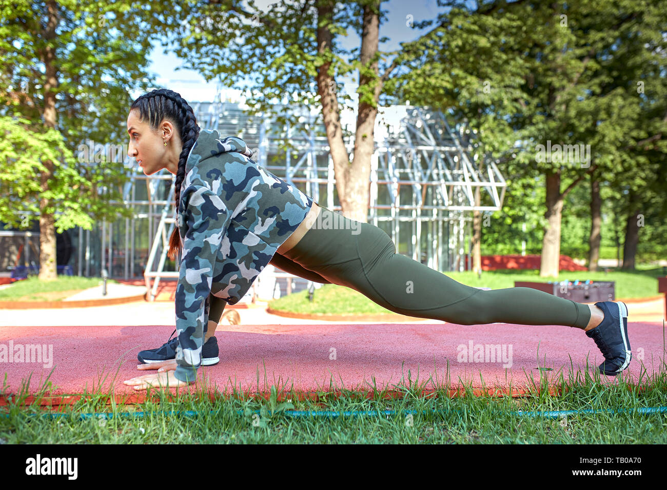 Concentrated young woman stretching legs and body doing yoga exercises ...