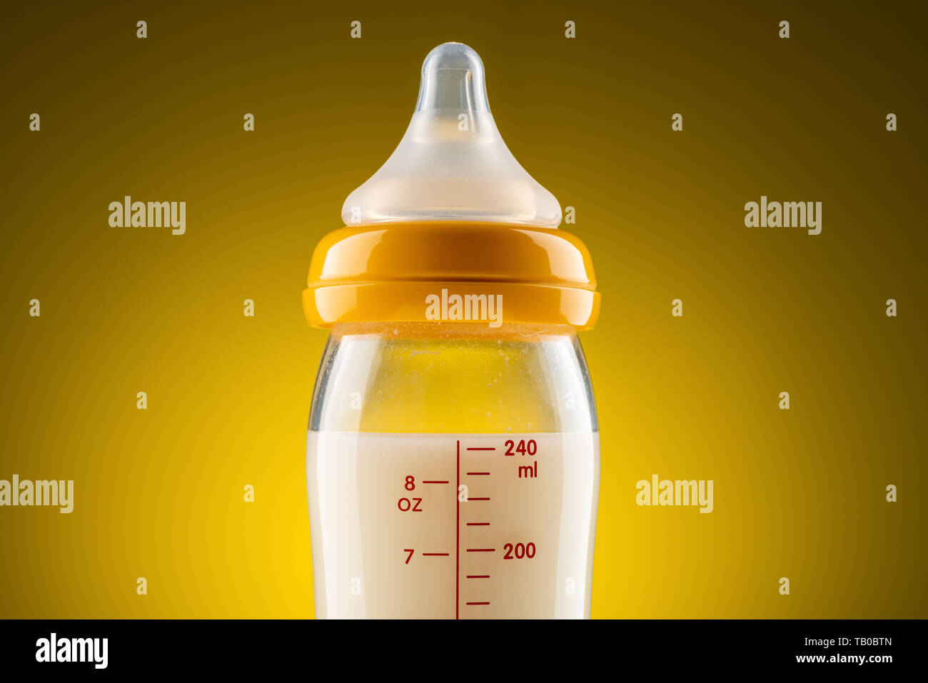 backlit glass baby bottle with powdered milk closeup on the upper part