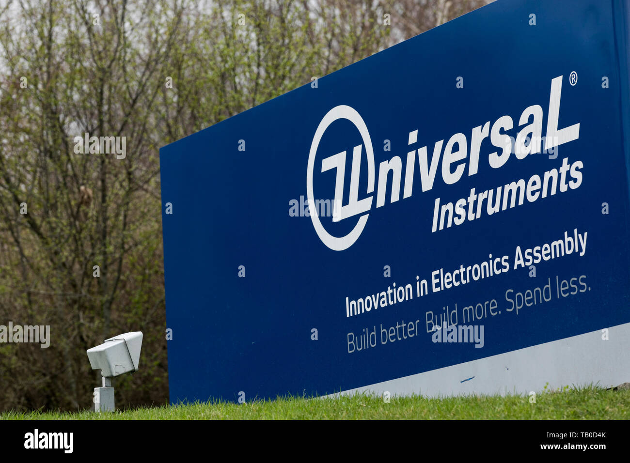A logo sign outside of the headquarters of Universal Instruments in