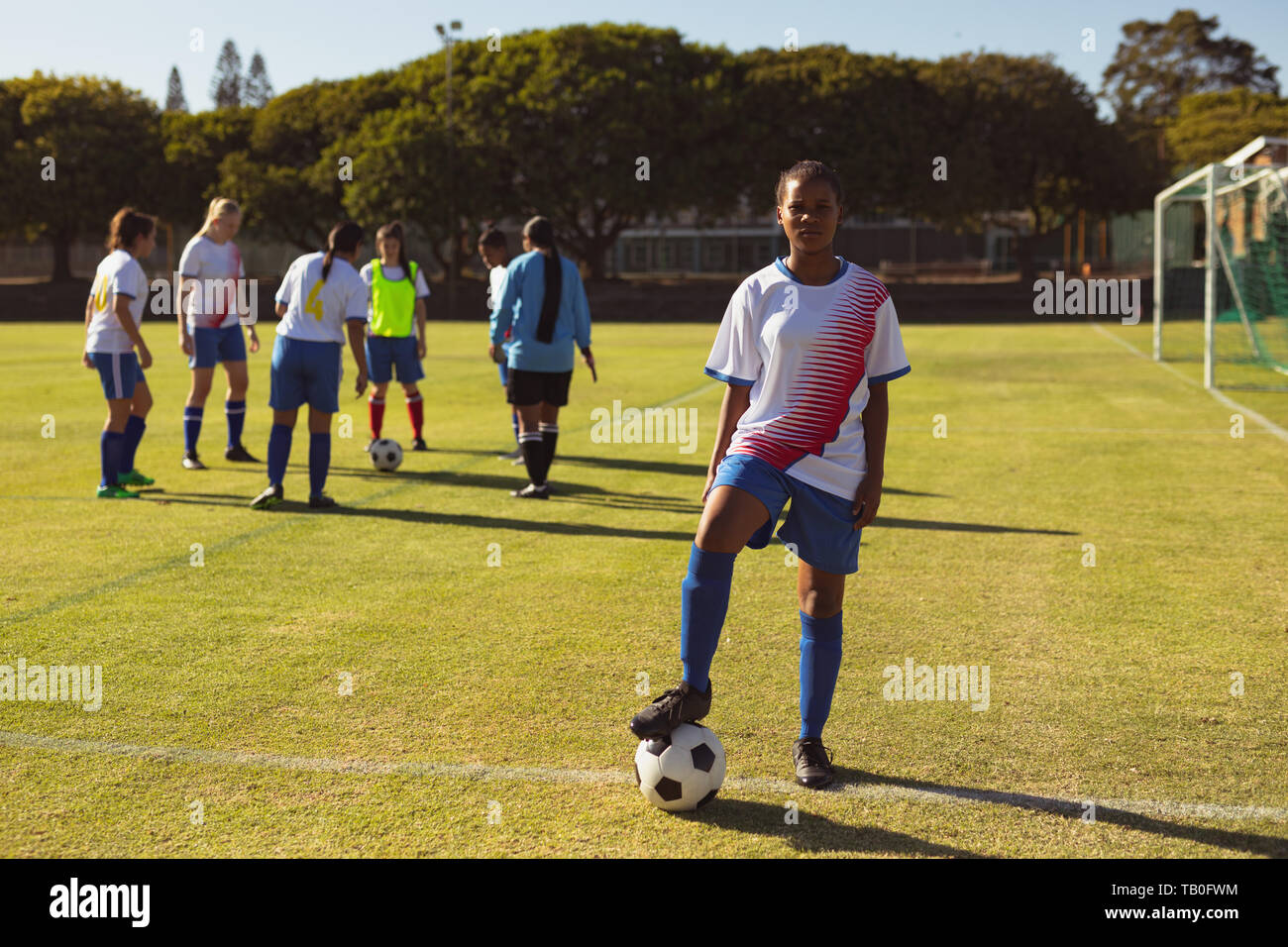 Female soccer player with ball standing at sports field Stock Photo