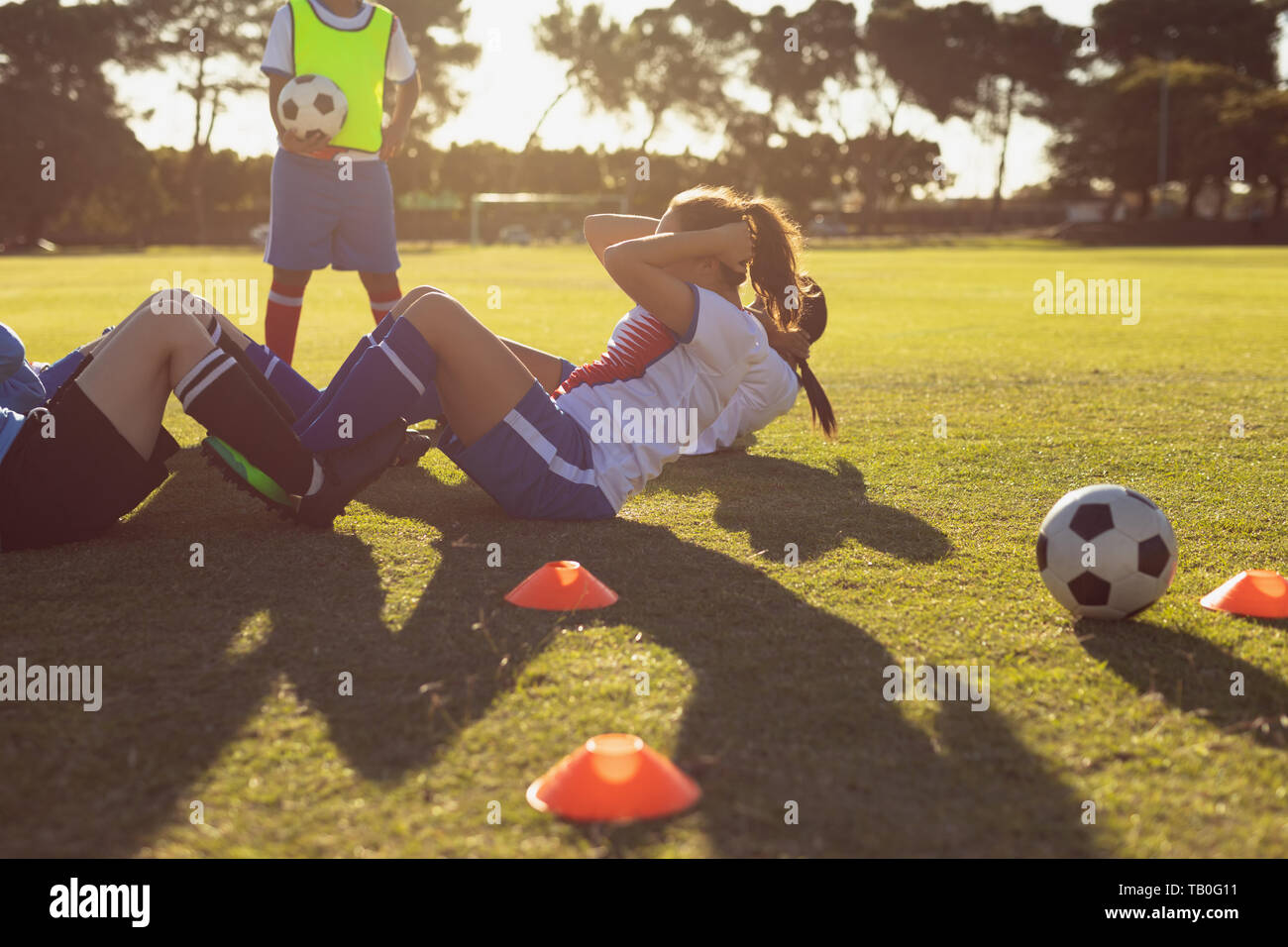 Determined female soccer players doing crunches on the field Stock Photo