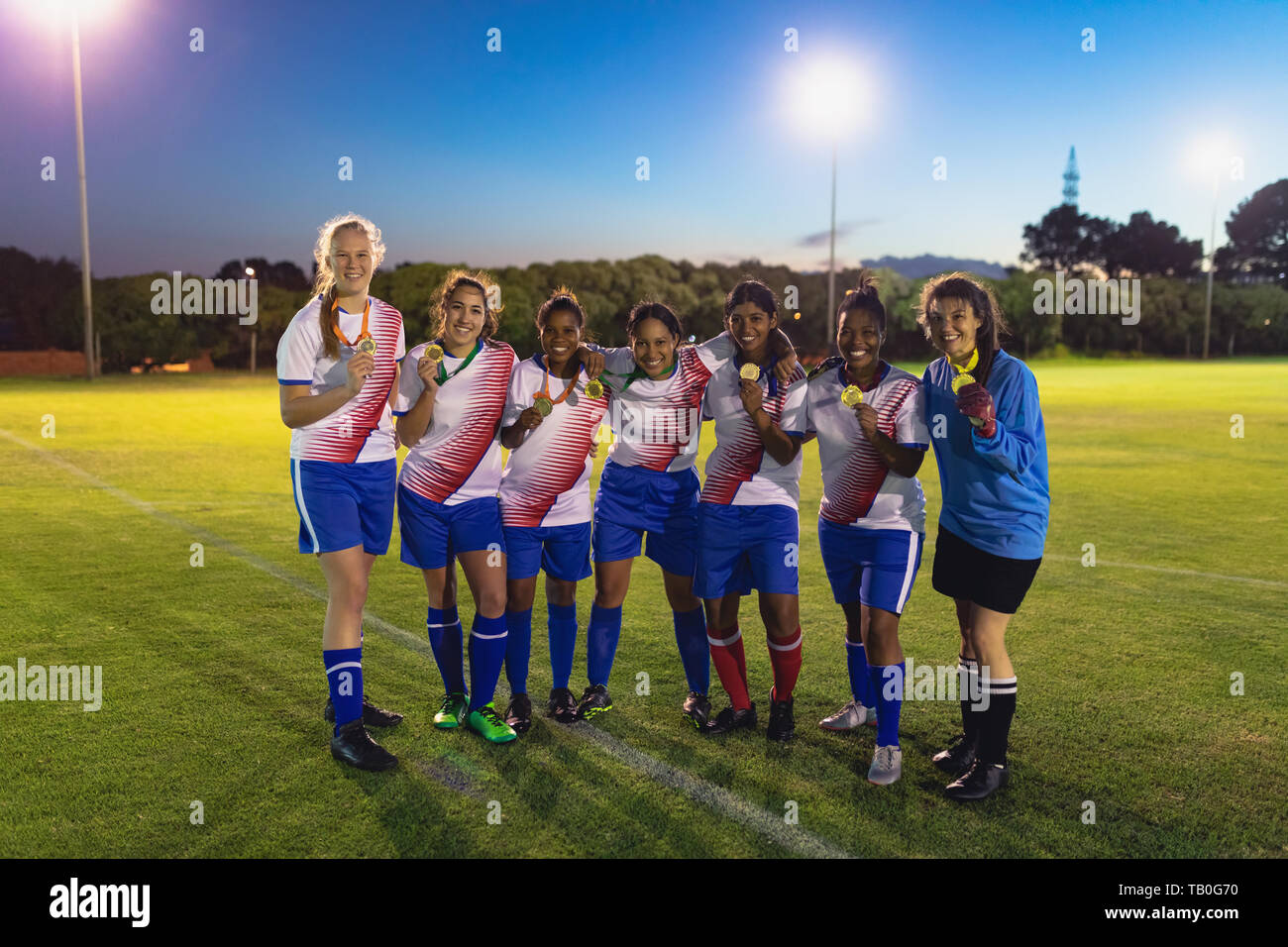 Portrait of soccer team posing with medal in sports field Stock Photo
