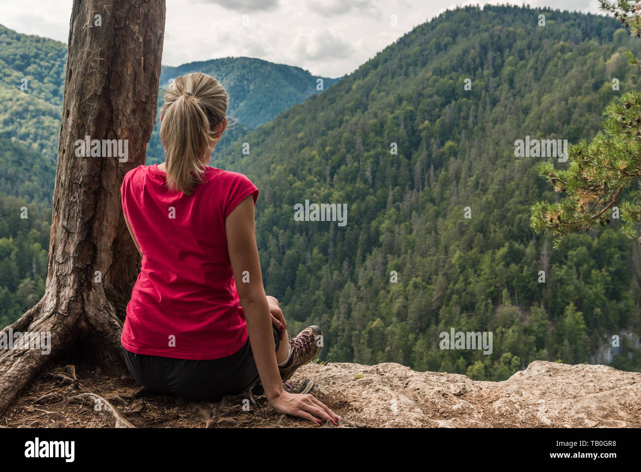 Girl sitting on a cliff looking on the mountains Stock Photo Alamy