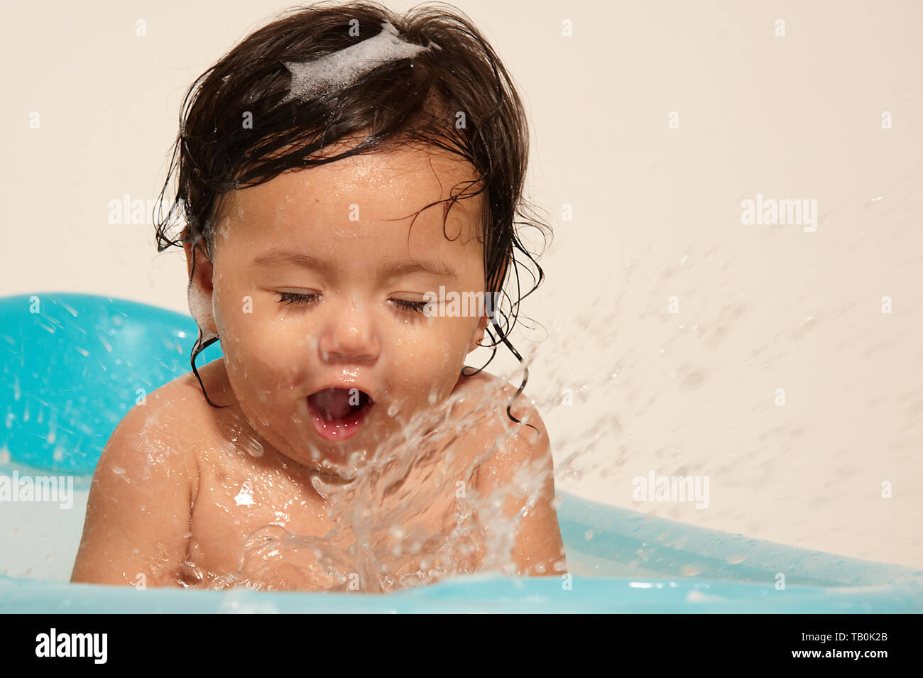 Super adorable cute baby girl happy and excited splashing in a ...