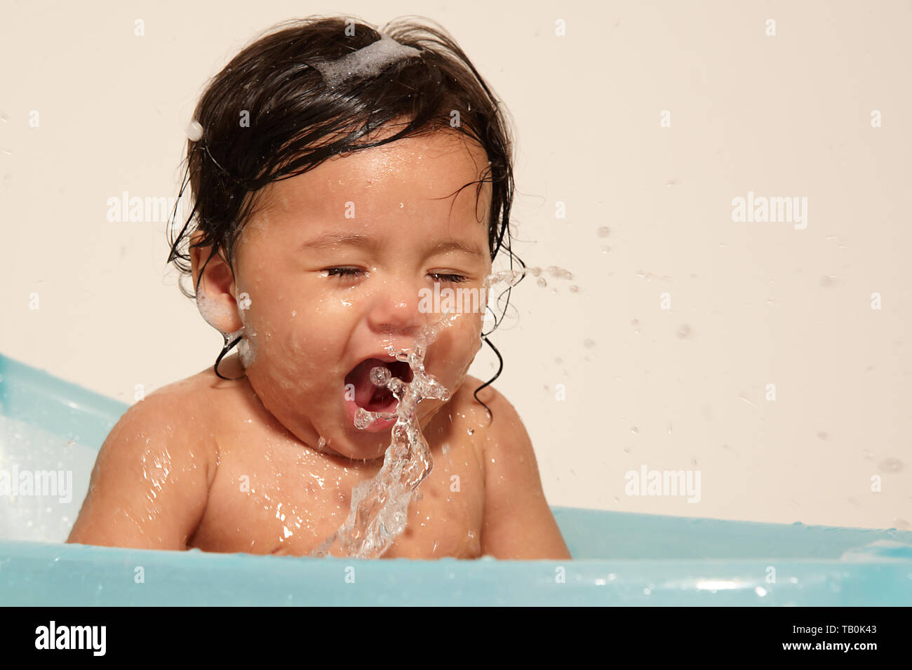 Super adorable cute baby girl happy and excited splashing in a ...
