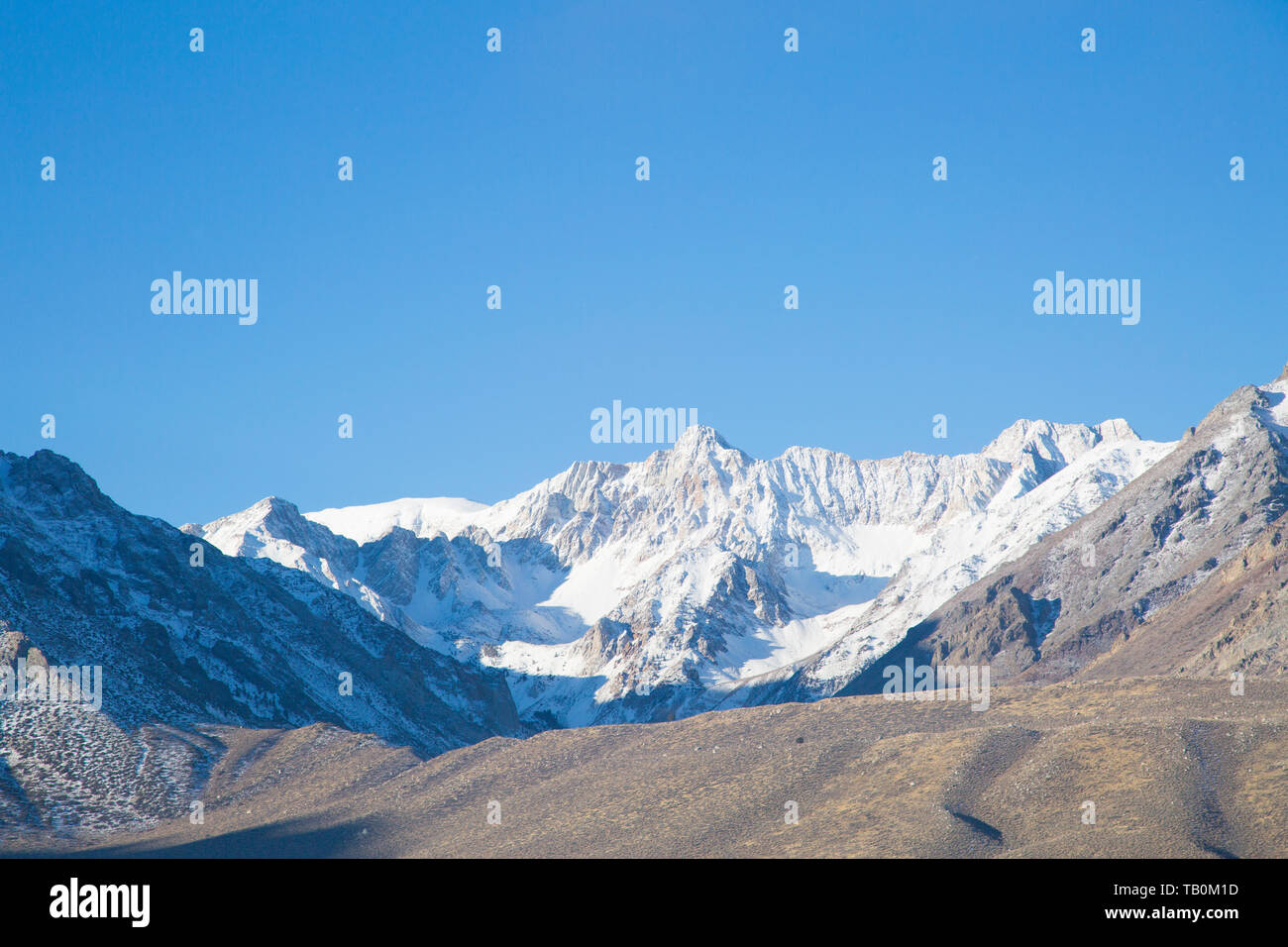 Snowcapped Sierra Nevada mountains in California, blue sky in background.  Hard shadows from morning light. Stock Photo