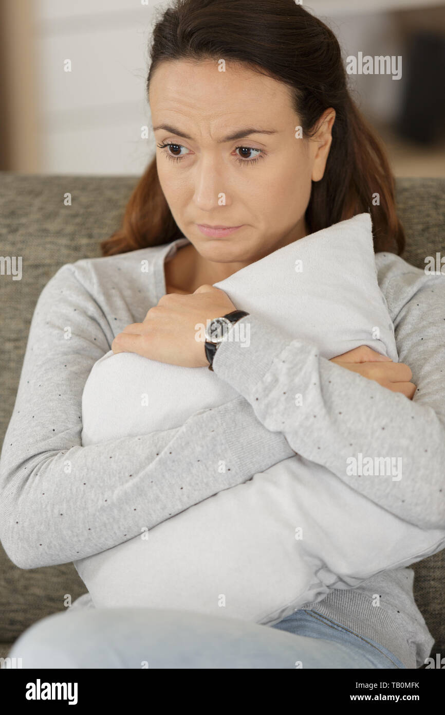 sad woman hugging pillow on the sofa Stock Photo - Alamy