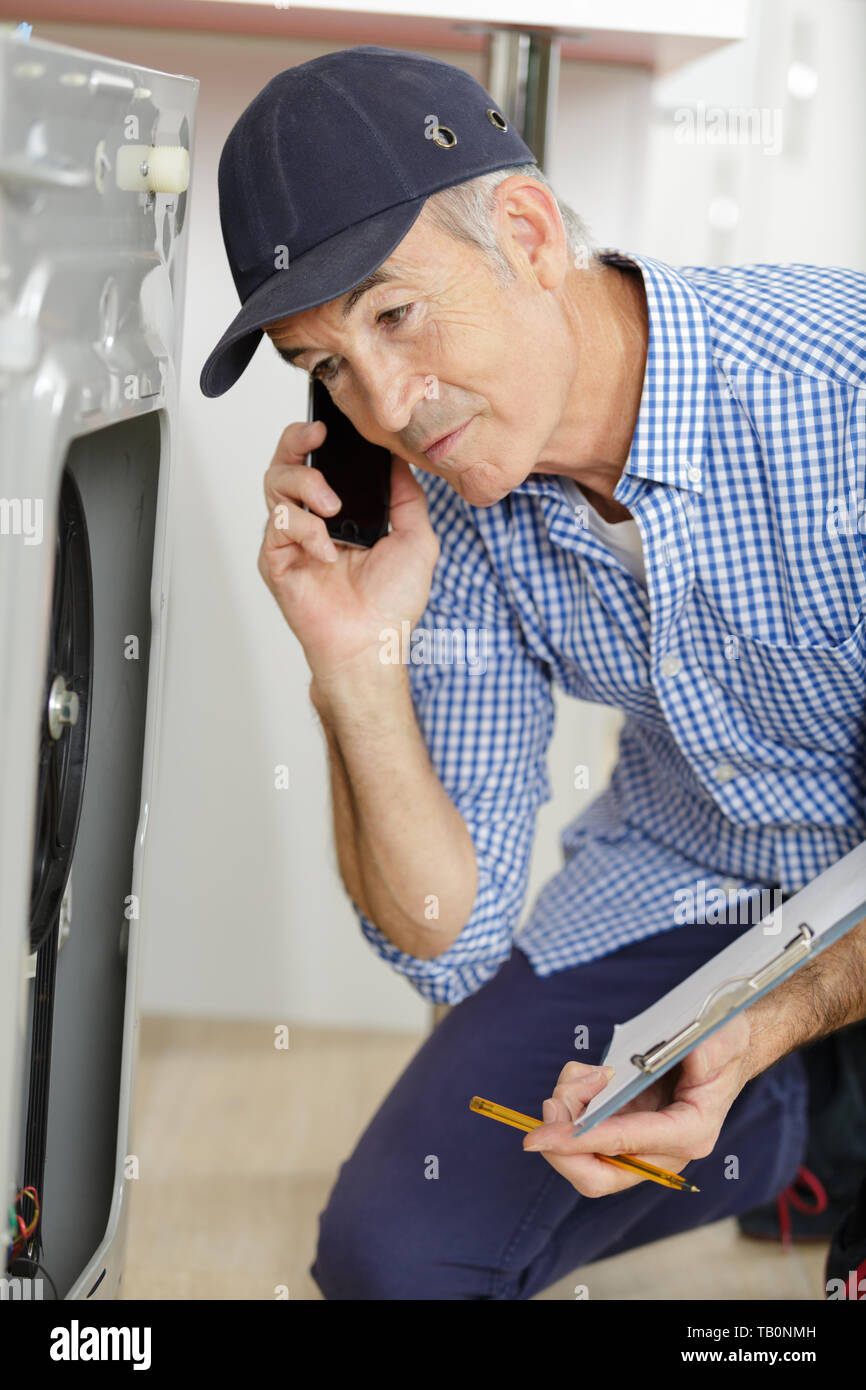 male technician on the phone checking a machine Stock Photo