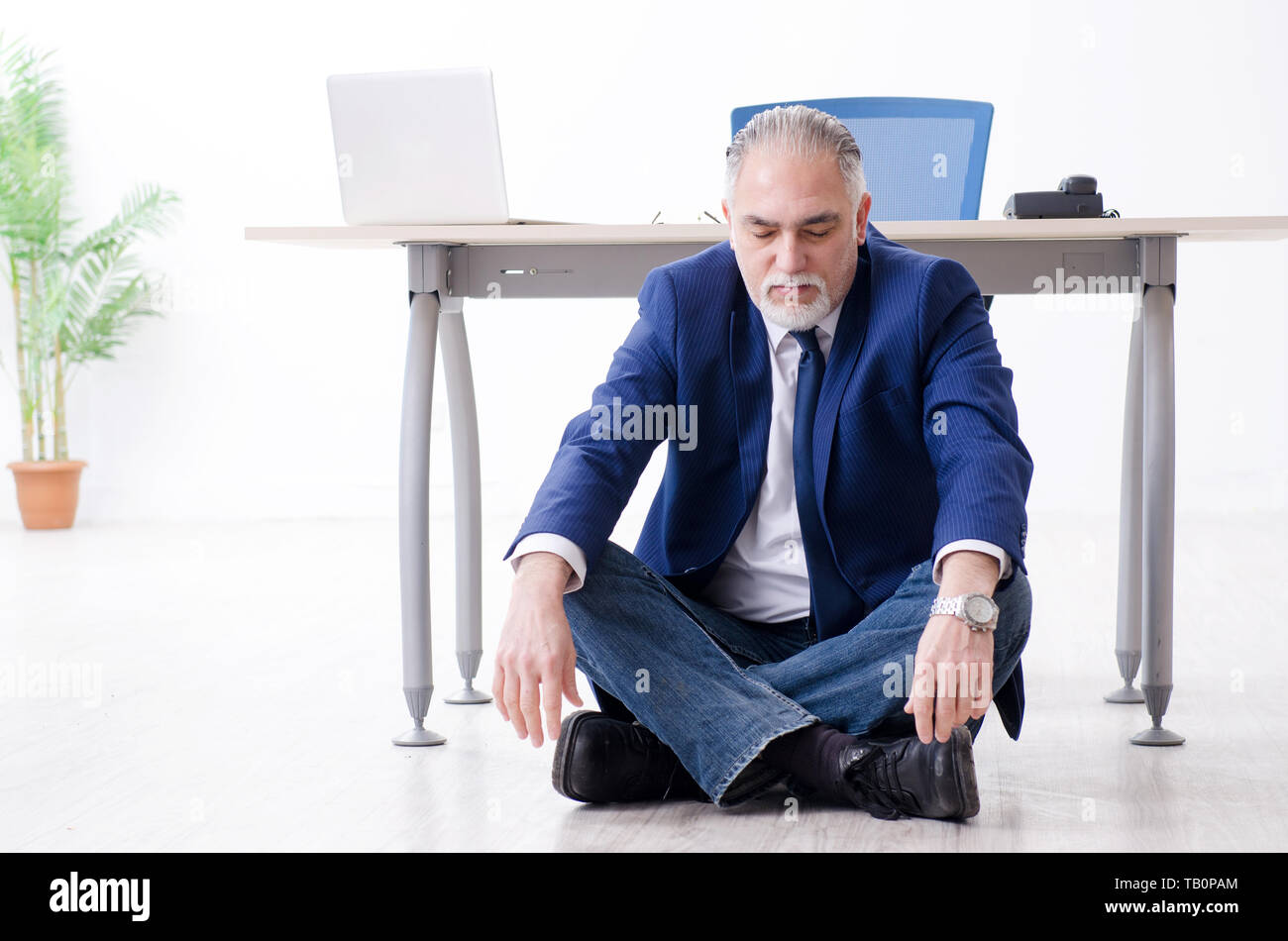 Aged businessman doing yoga exercises in the office Stock Photo - Alamy