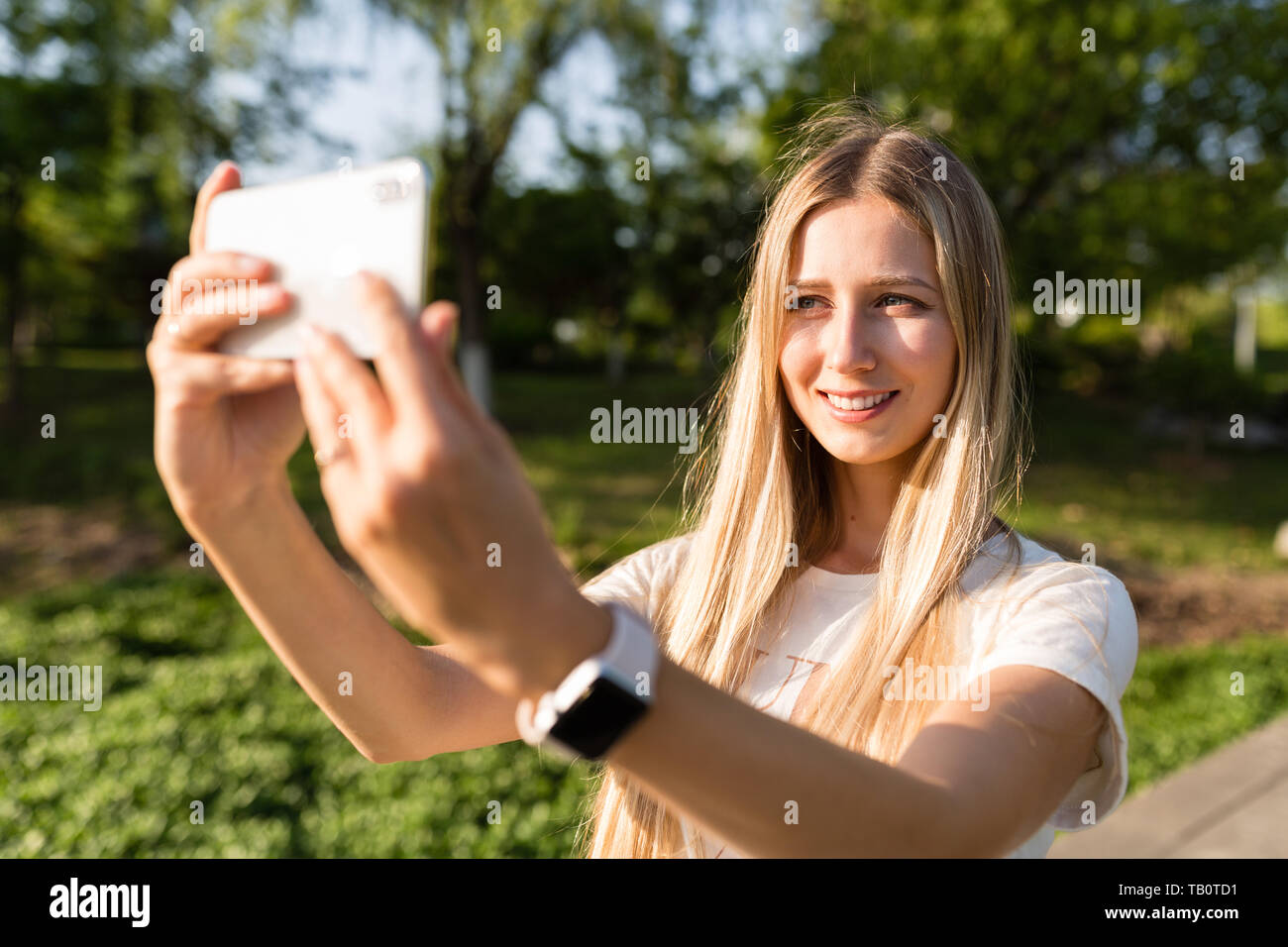 Beautiful Young Woman With Blonde Hair Using Mobile Phone Outdoor