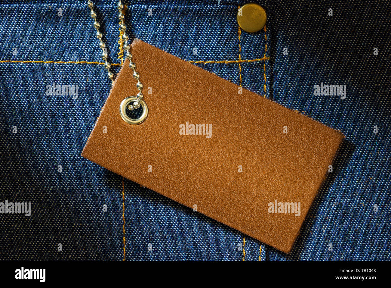 Leather label of product price and stainless steel ball chain on denim clothing. The concept of Fashion jeans. Stock Photo