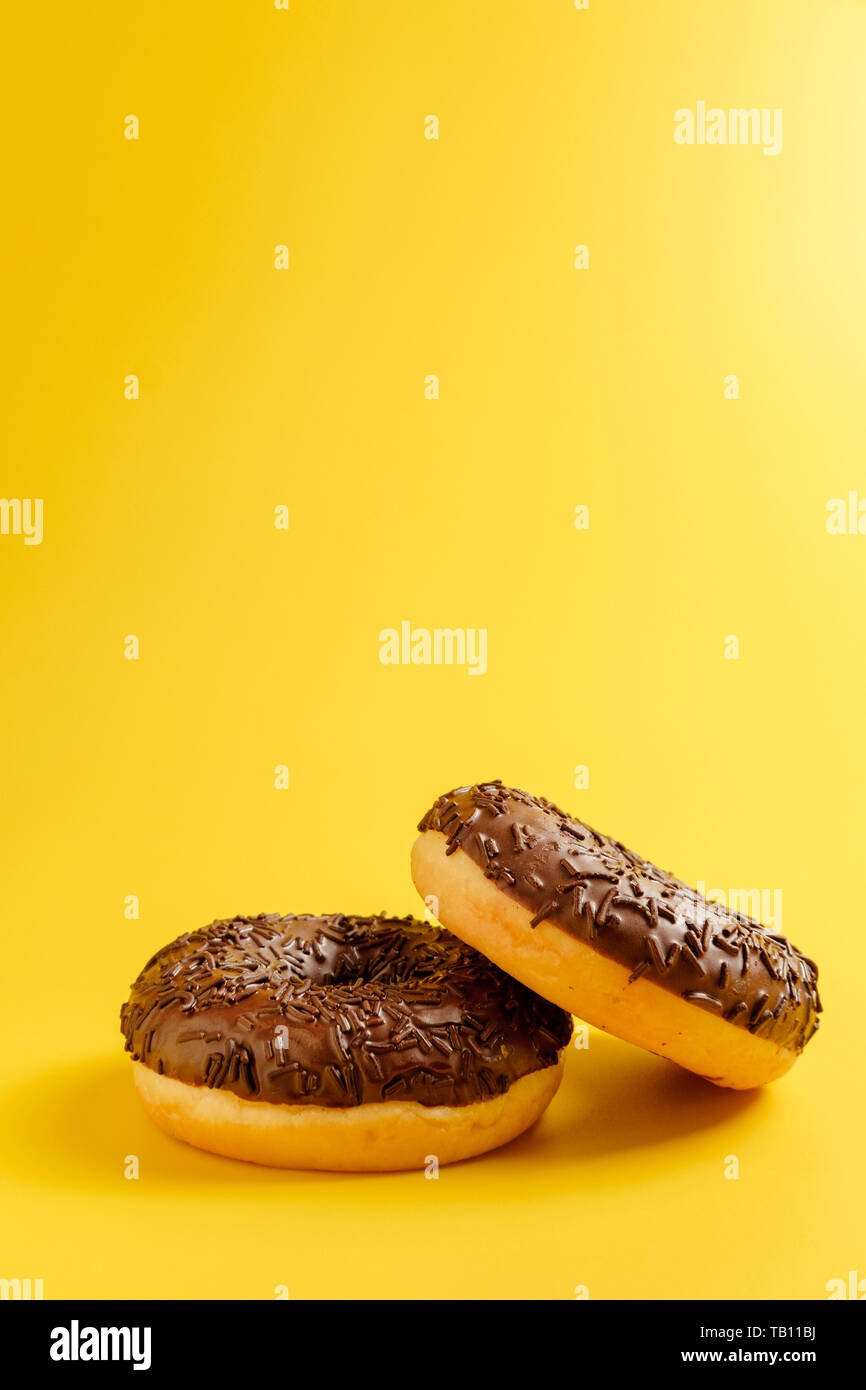 black donuts on yellow background top view Stock Photo