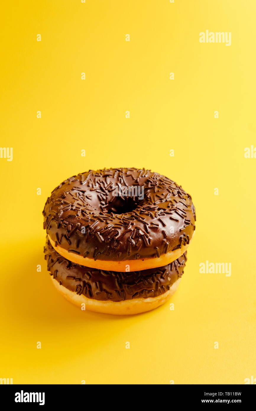 black donuts on yellow background top view Stock Photo