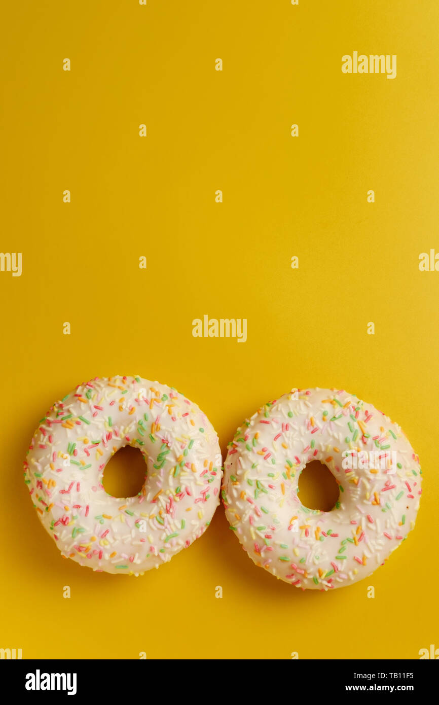 two white donuts on yellow background top view copy space Stock Photo