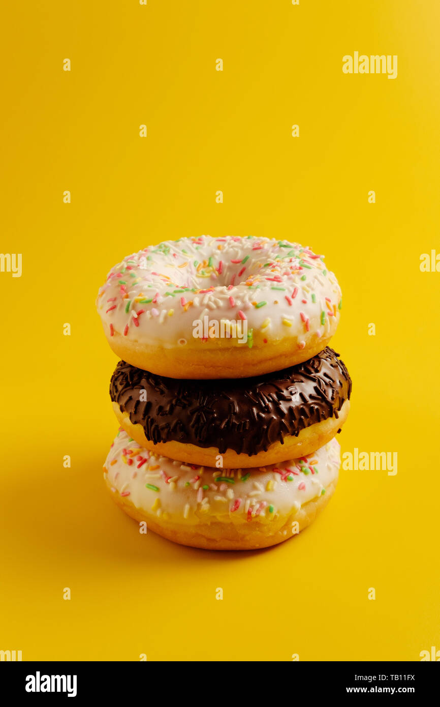 three white and black donuts on yellow background copy space Stock Photo