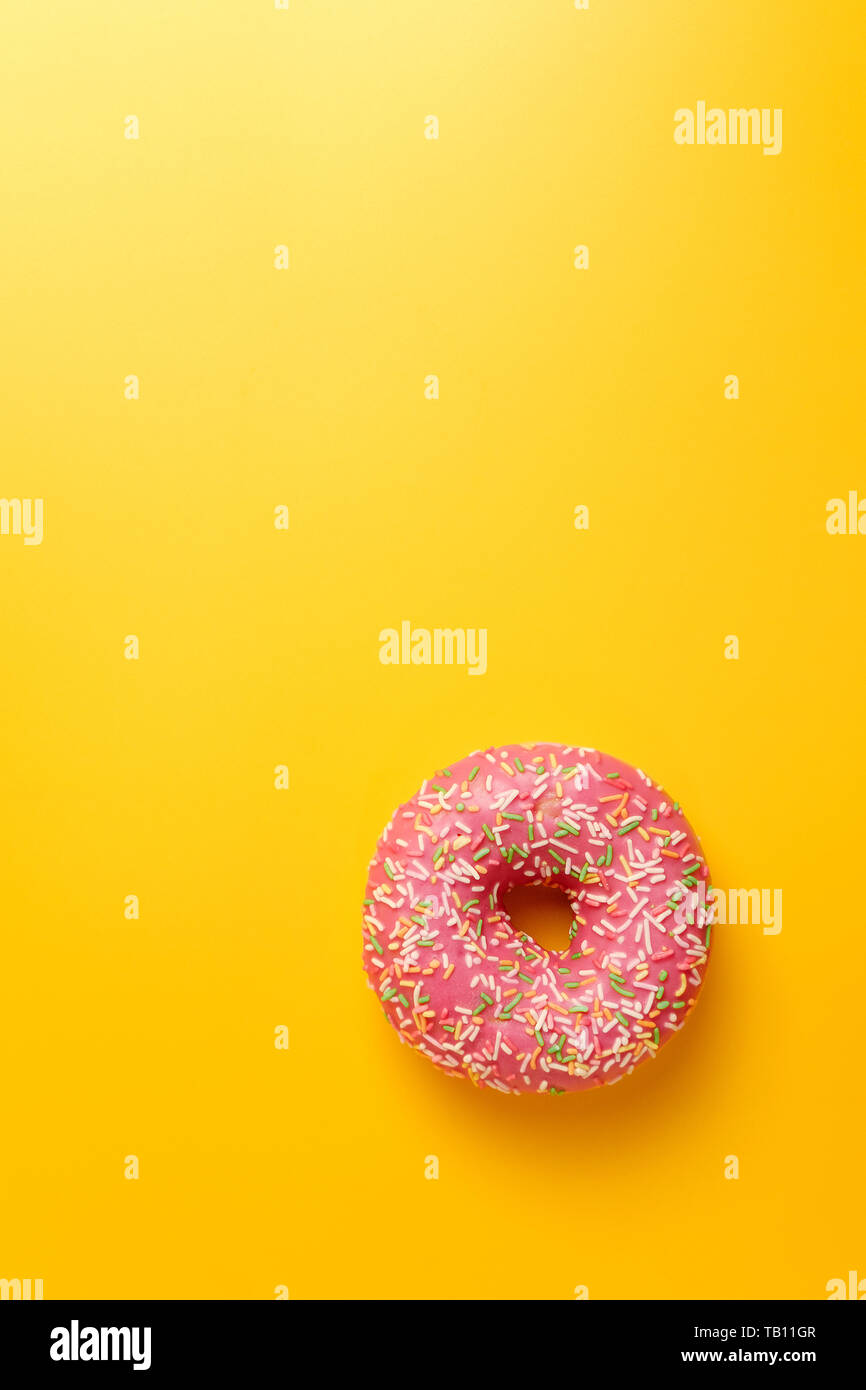 pink donut on yellow background top view Stock Photo - Alamy